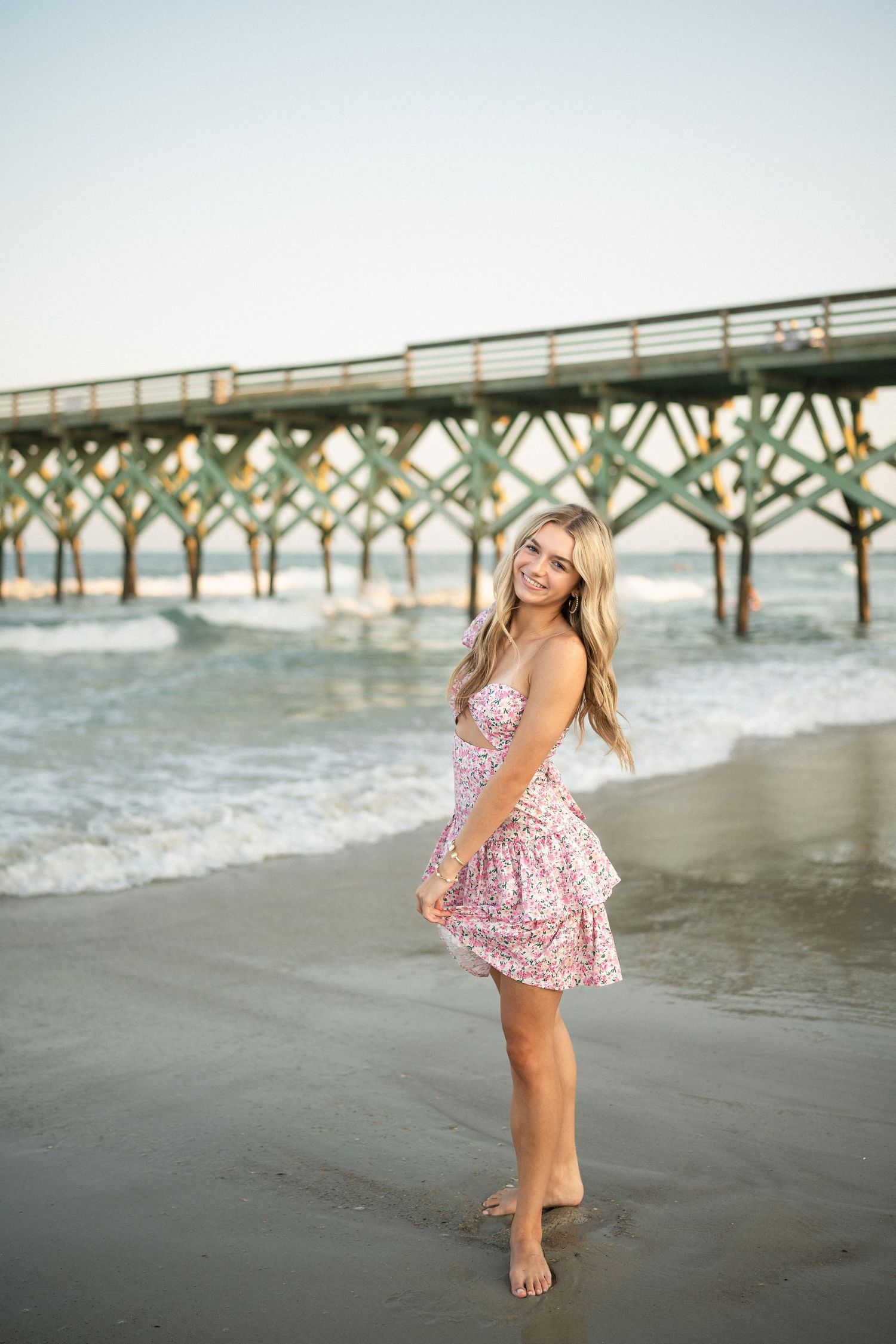 Senior portrait of Sydney at Wilmington, NC pier, showcasing a ocean backdrop during a beachside photo session
