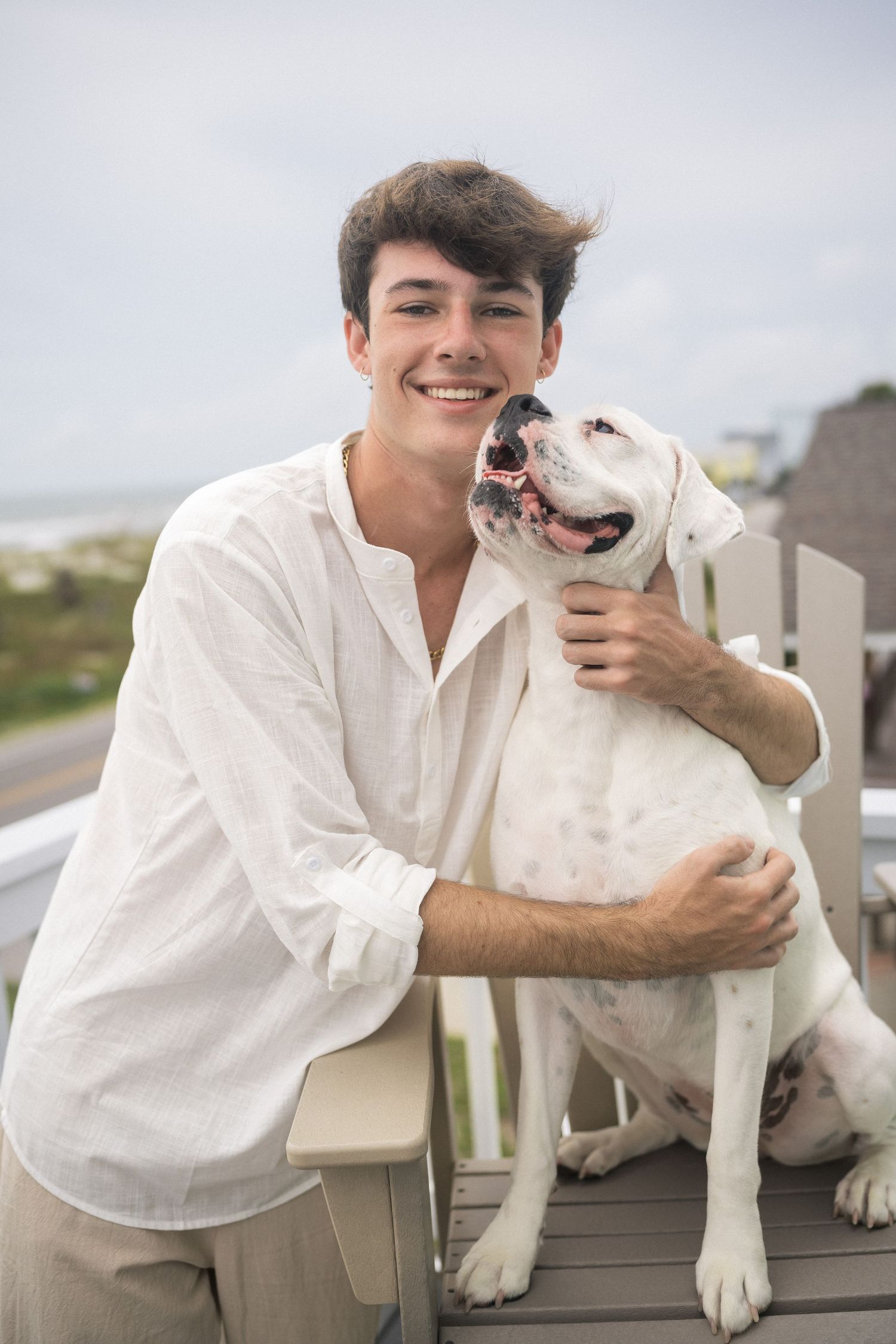 High school senior guy sitting with his dog on Oak Island Beach in North Carolina