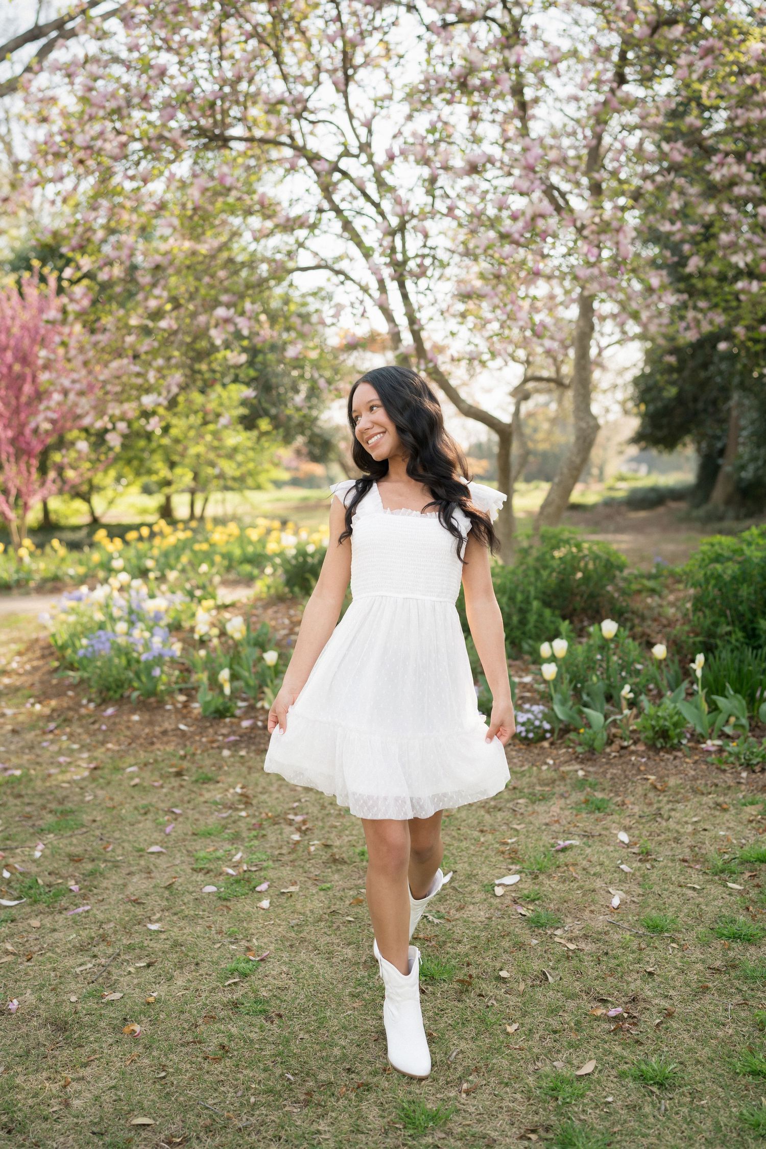 High school senior girl walking and holding her dress at Fred Fletcher Park in Raleigh during a spring session.
