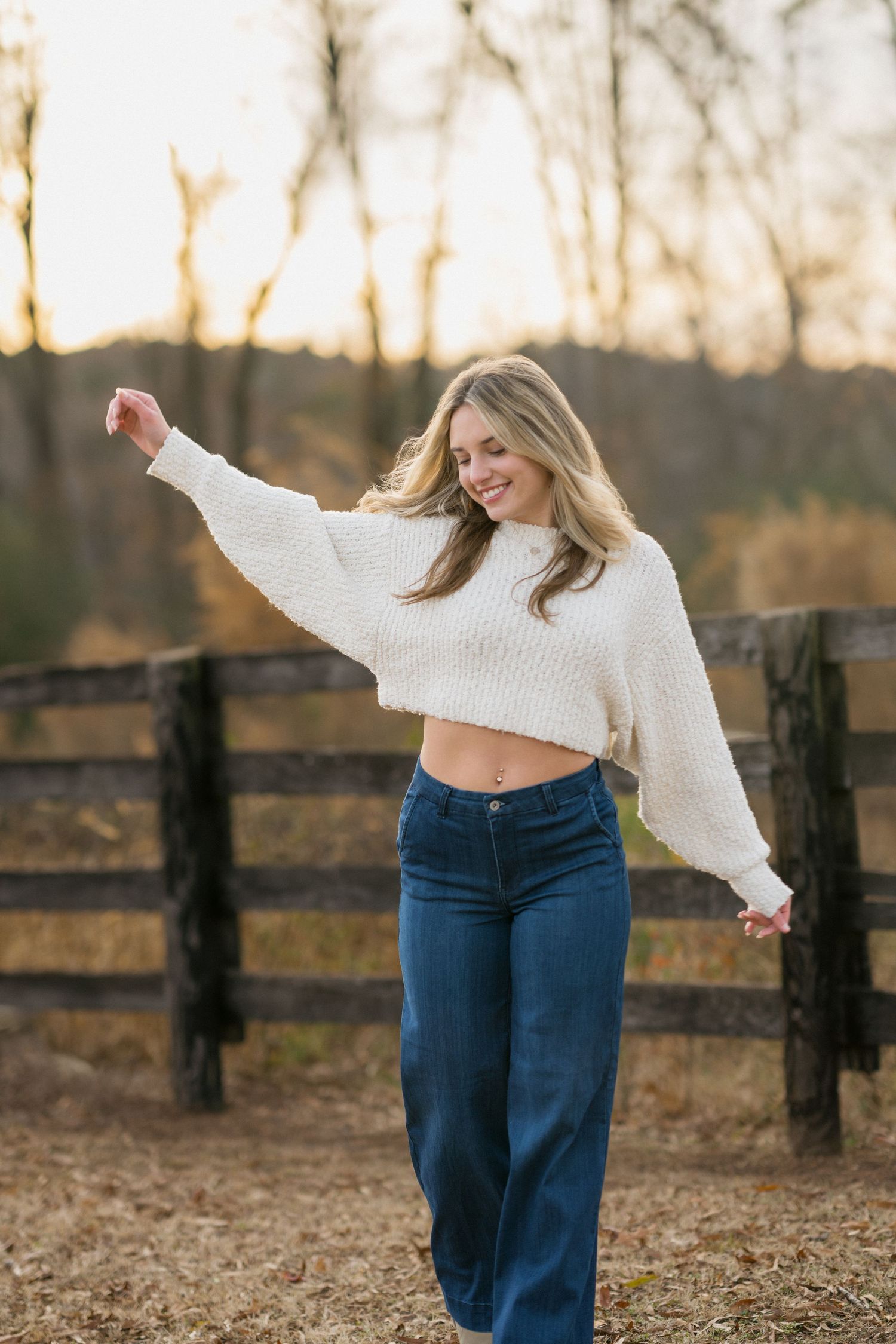 High school senior girl walking toward the camera playfully at Sugg Farm in Holly Springs during a winter session.