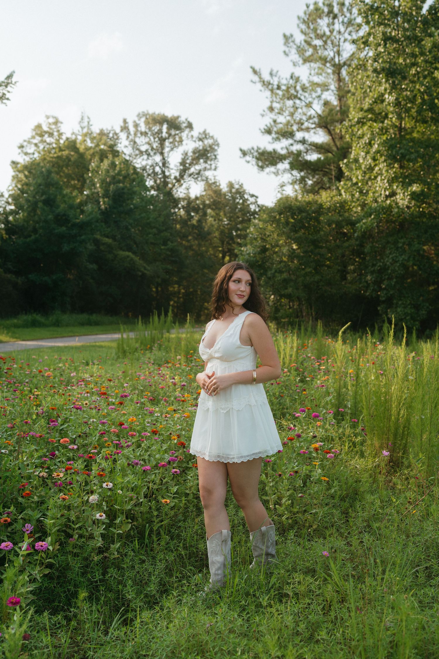 High school senior girl in a white dress walking in the wildflowers in Raleigh, North Carolina.