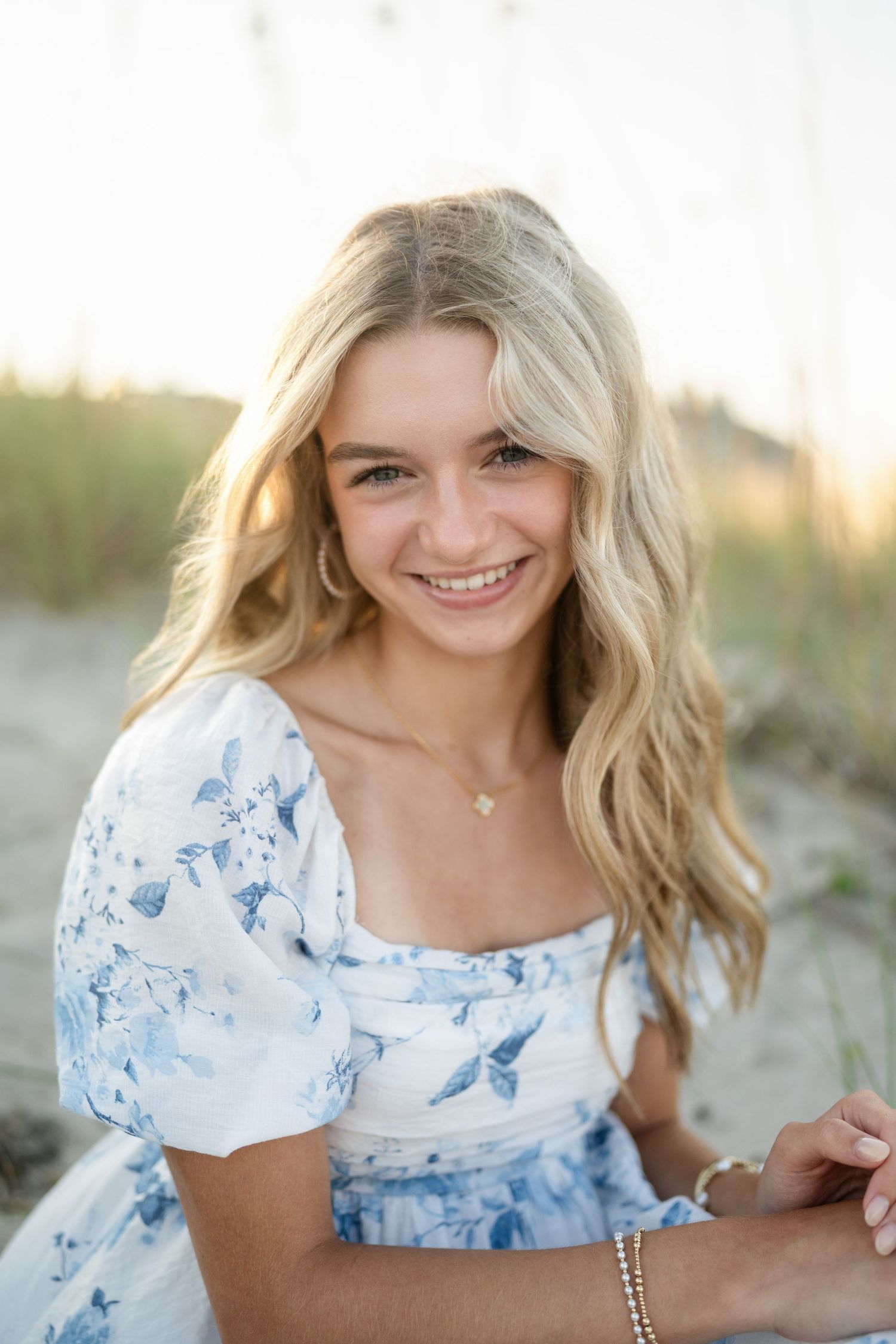 Sydney's senior photo session on Wilmington, NC beach, sitting in the sand during golden hour