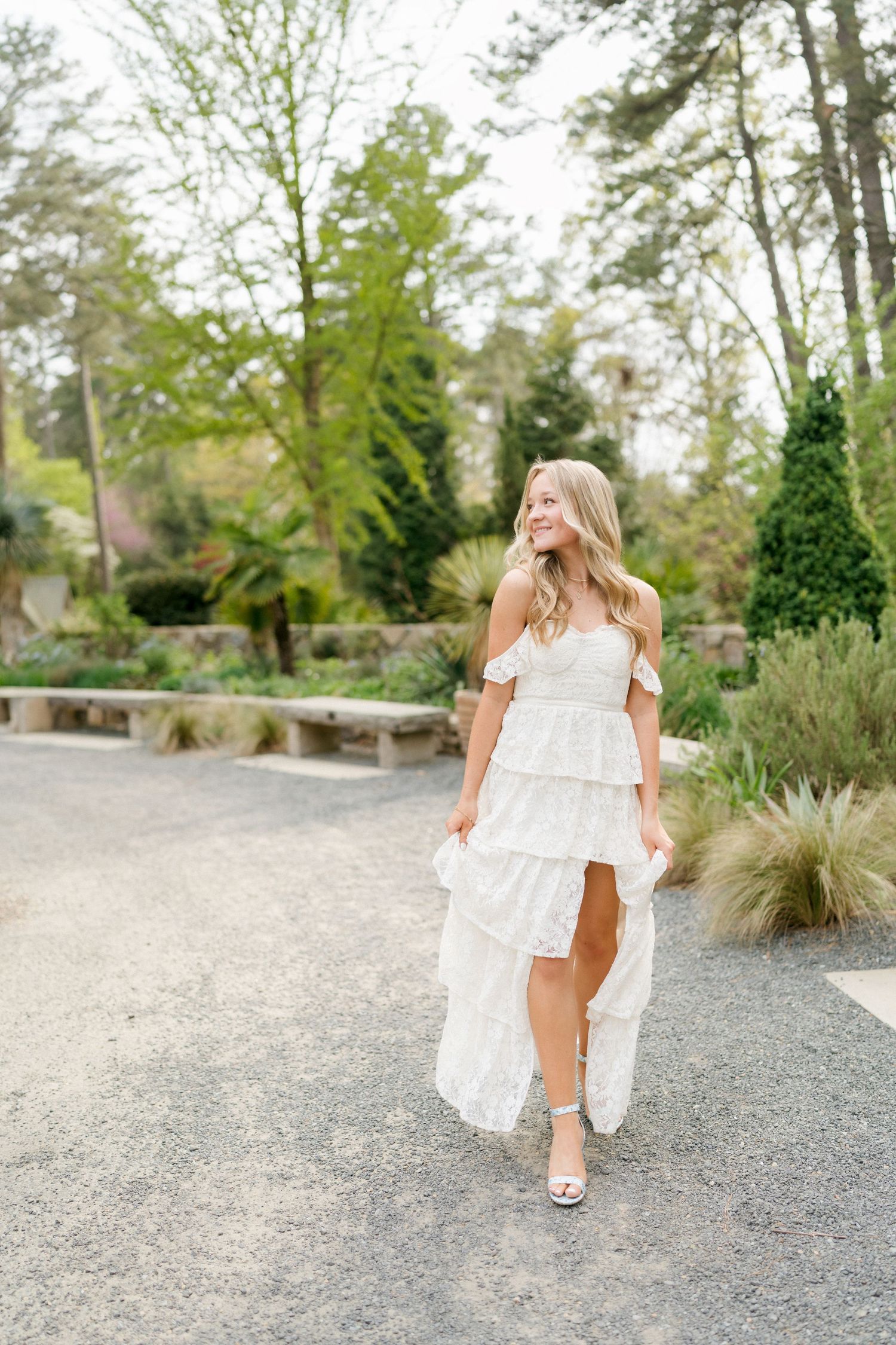 High school senior girl walking and holding her dress at Duke Gardens in Durham during a spring senior photo session.