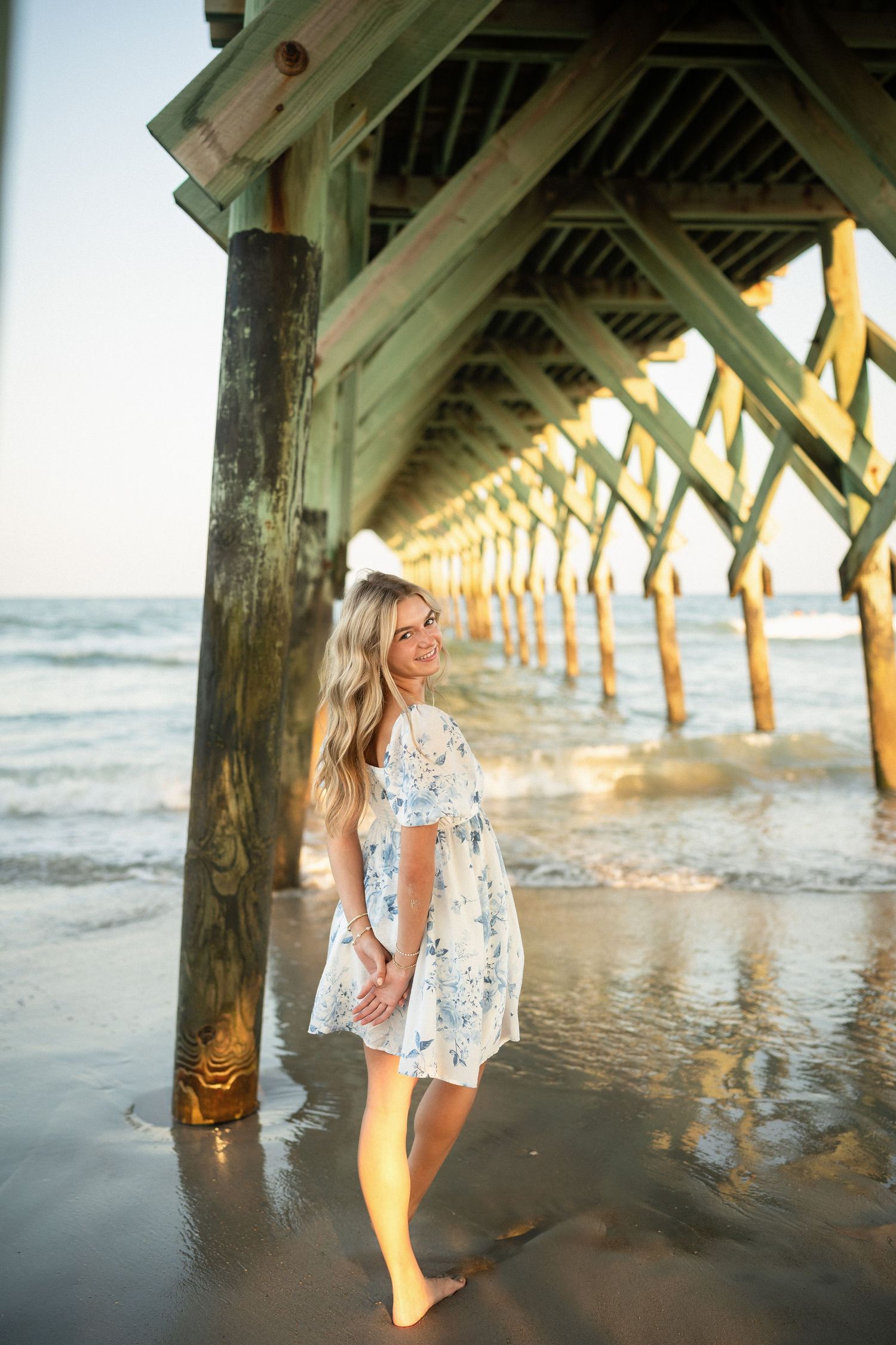 Senior portrait of Sydney at Wilmington, NC pier, showcasing a ocean backdrop during a beachside photo session