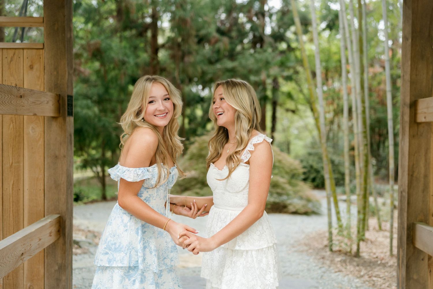 Twin high school seniors laughing and holding hands during their spring session at Duke Gardens in Durham.