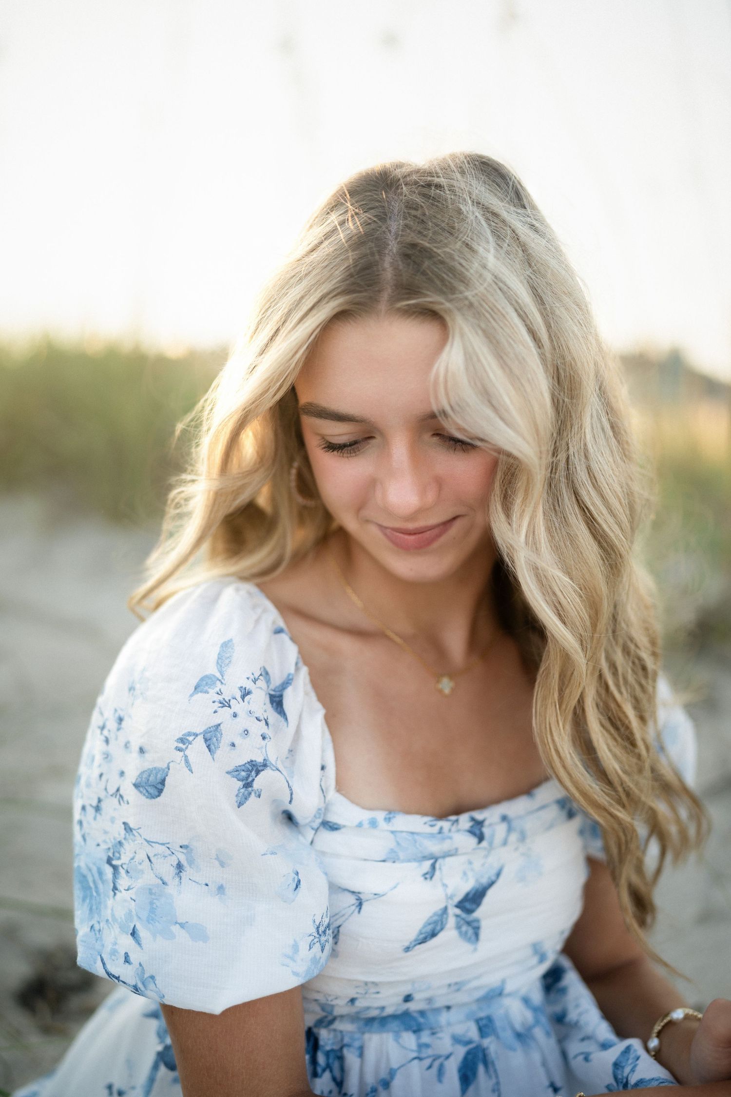 Sydney's senior photo session on Wilmington, NC beach, sitting in the sand during golden hour