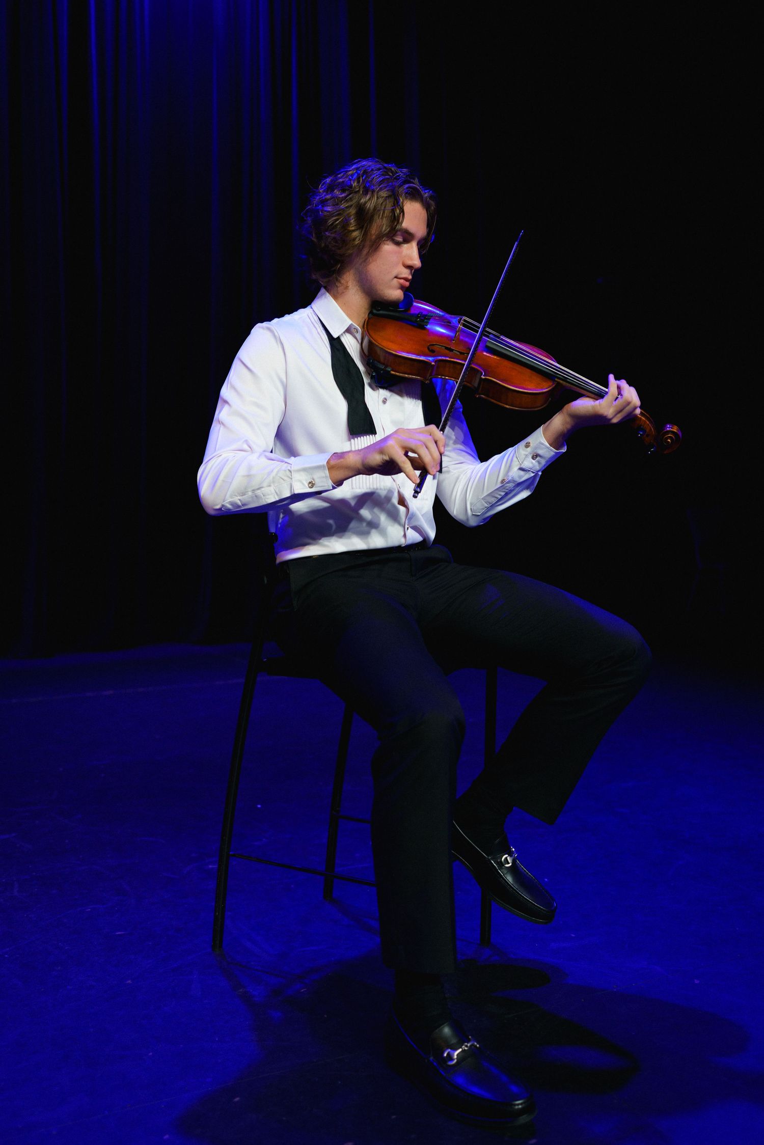 Dramatic stage portrait of high school senior guy playing violin in Clayton, NC