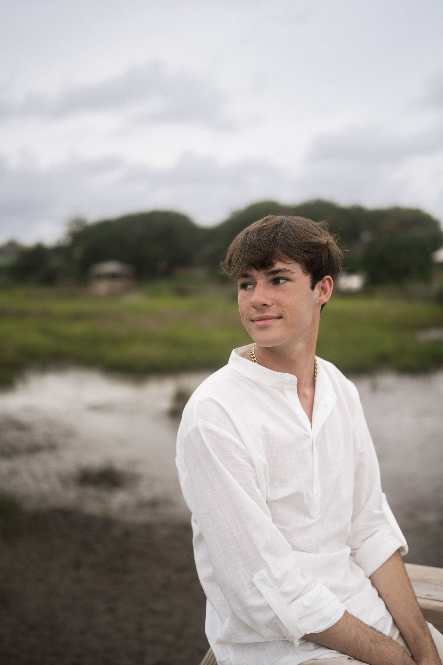 High school senior sitting on dock at Oak Island Beach in North Carolina