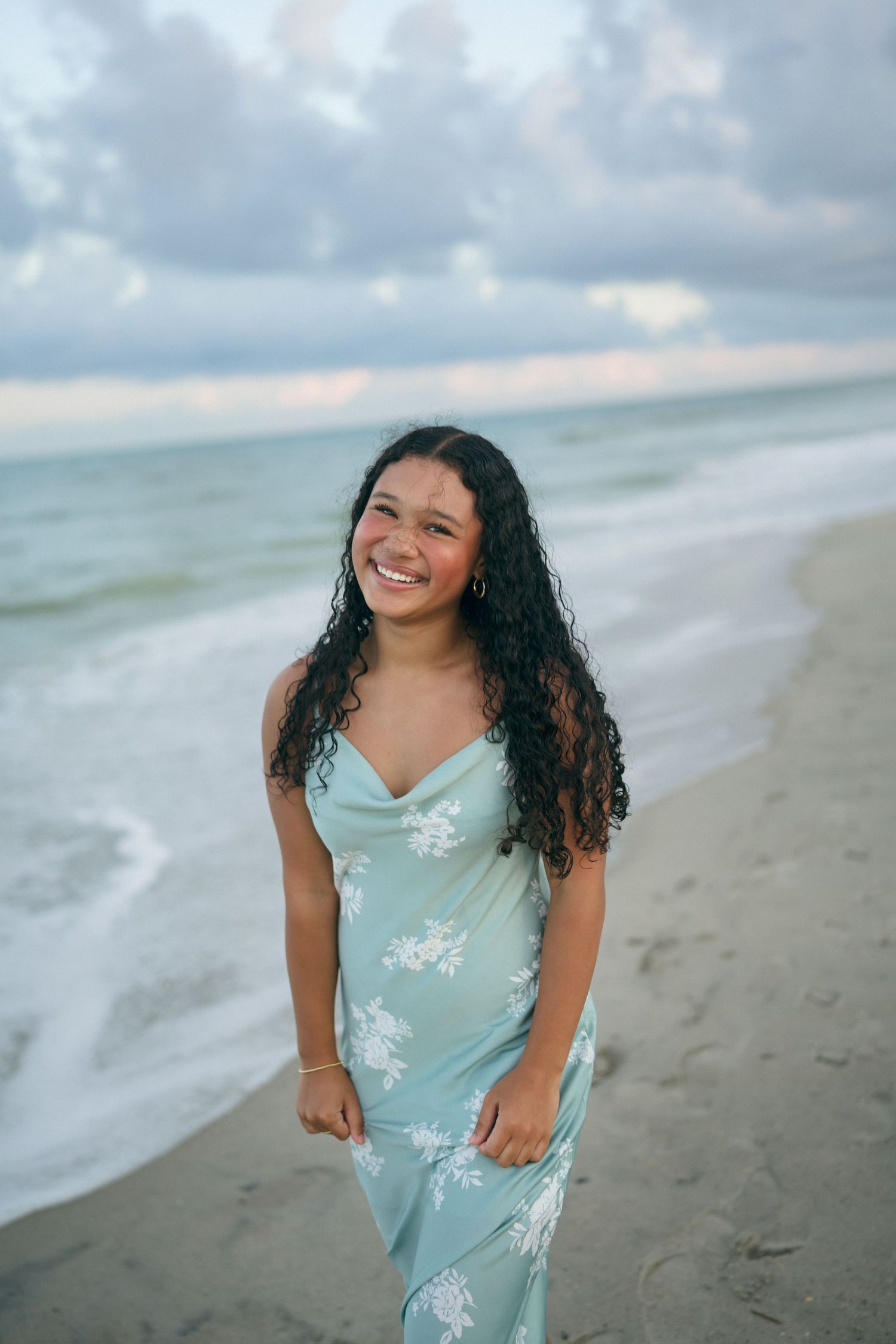 High school senior girl smiling while walking in the sand during her senior photo session at Carolina Beach, North Carolina.