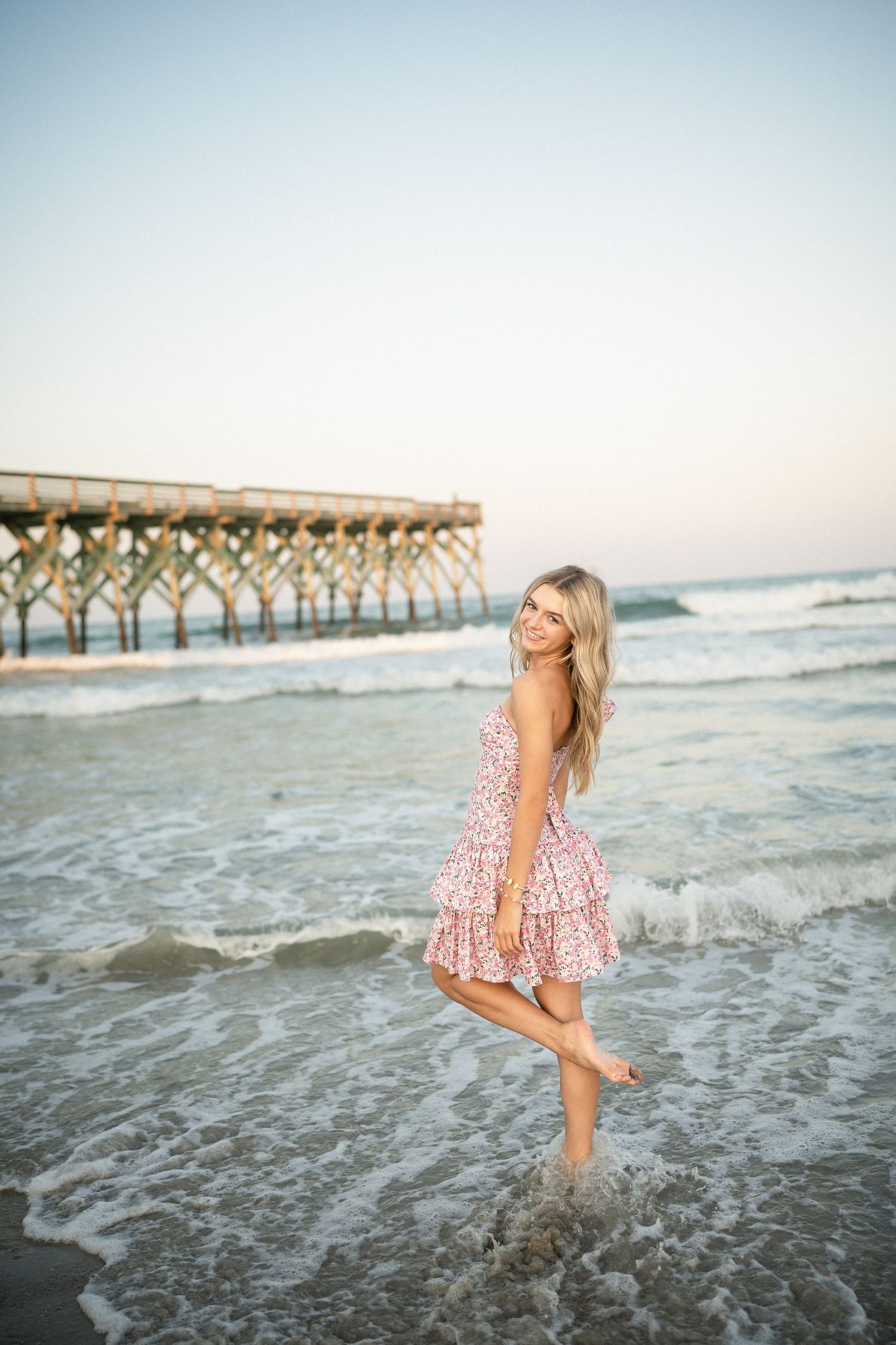 Senior portrait of Sydney at Wilmington, NC pier, showcasing a ocean backdrop during a beachside photo session