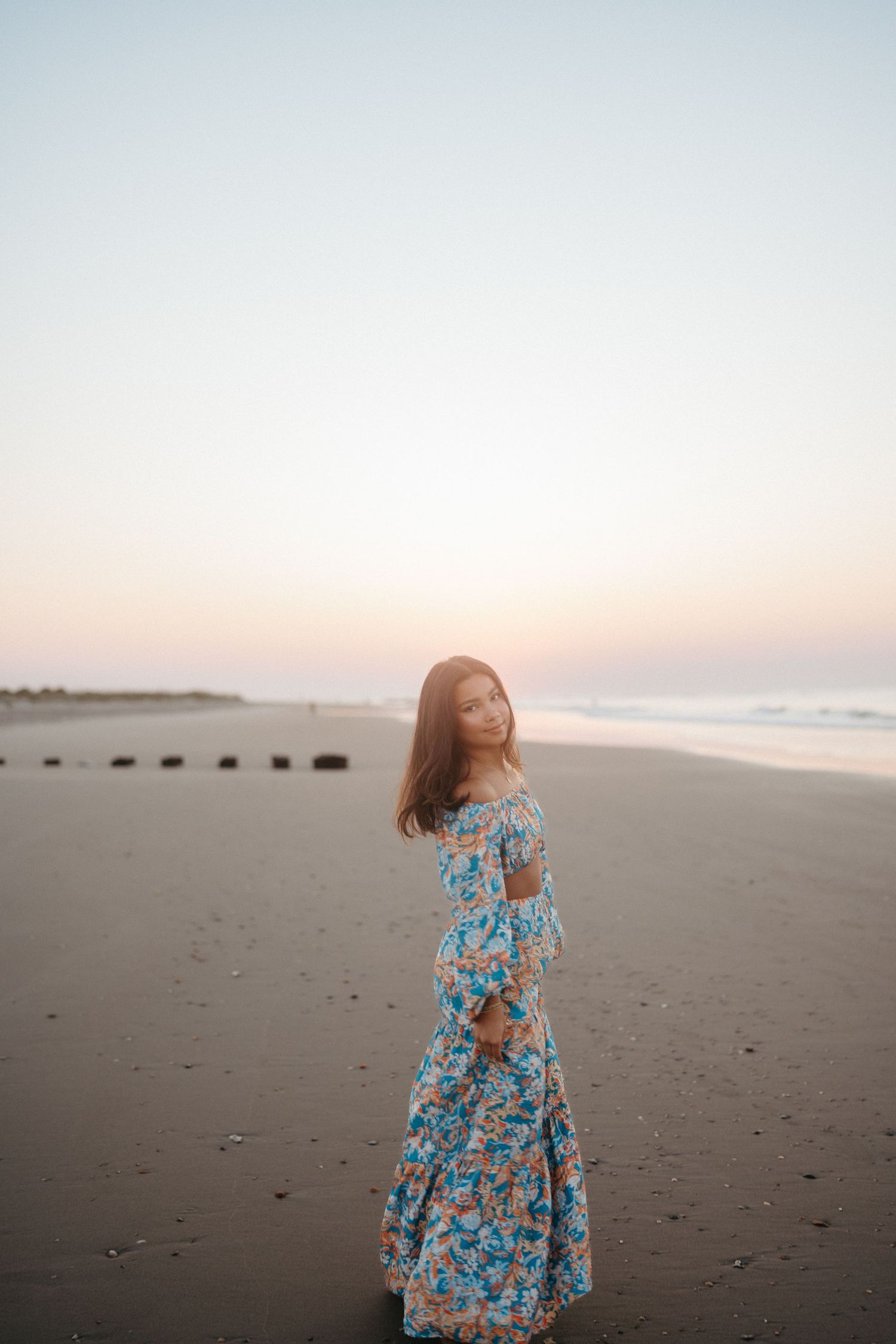 High school senior girl walking toward the sunrise on Folly Beach, South Carolina.