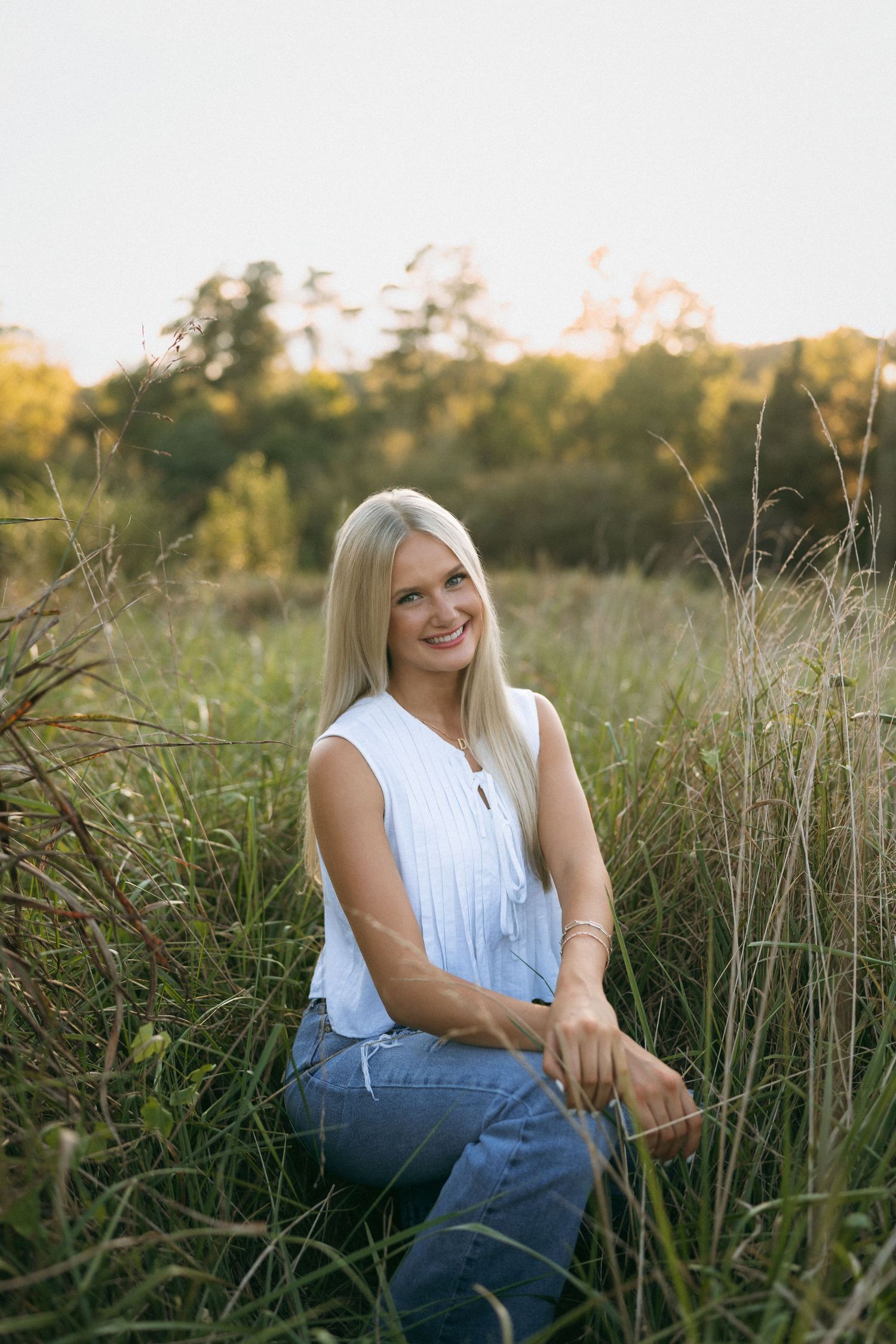 High school senior girl standing in a field during golden hour at Yates Mill in Raleigh, North Carolina.