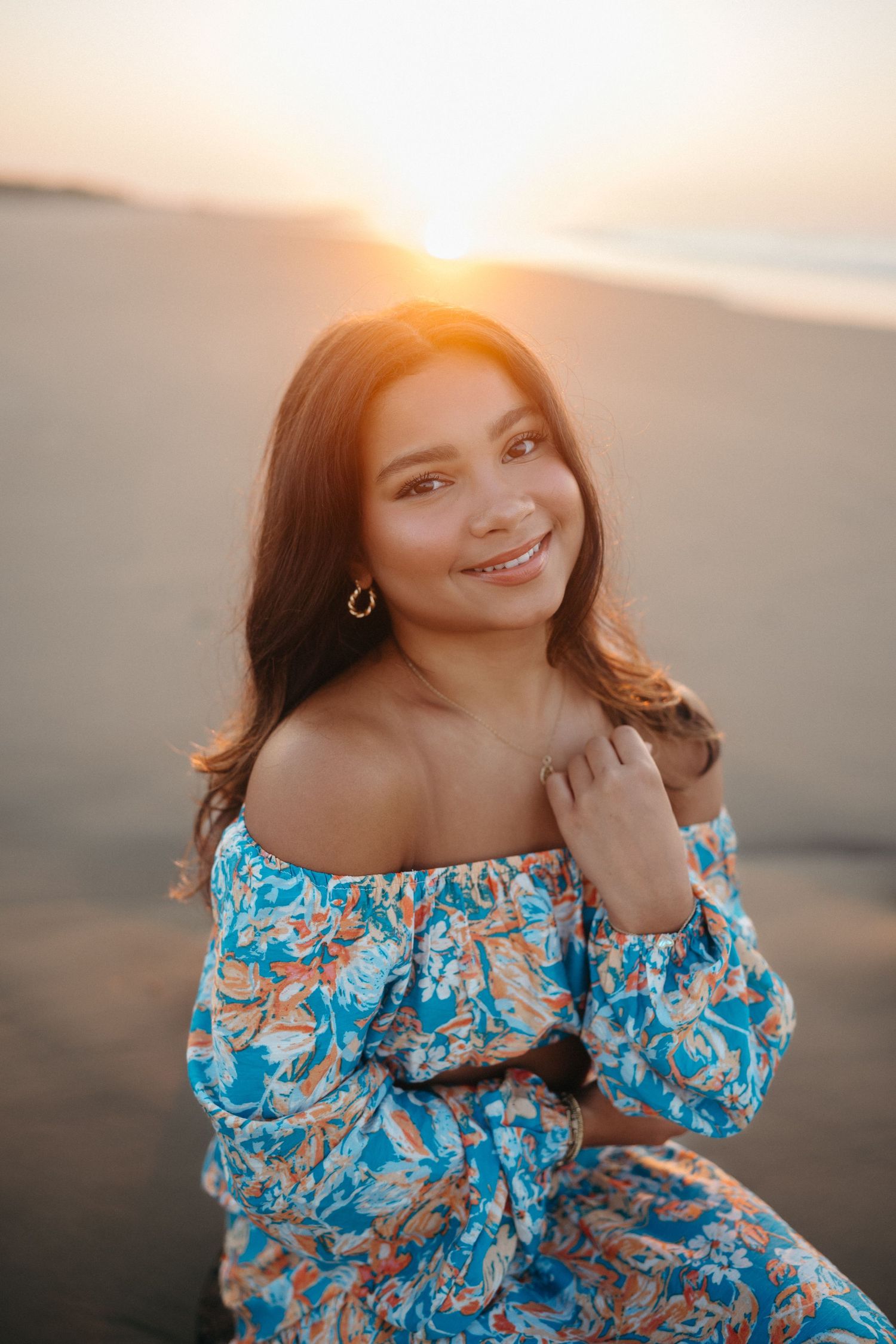 Close-up of a high school senior girl at sunrise on Folly Beach, South Carolina with sunlight behind her.