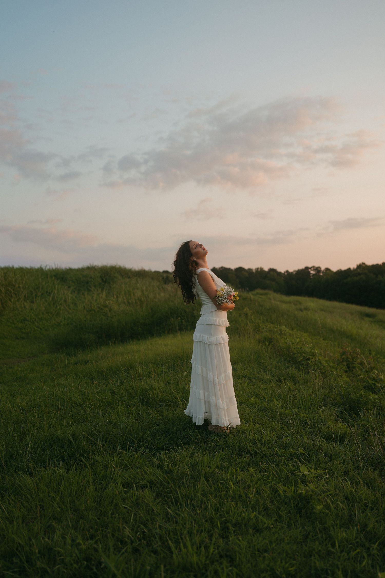 High school senior girl in a white dress holding flowers in Raleigh, North Carolina.