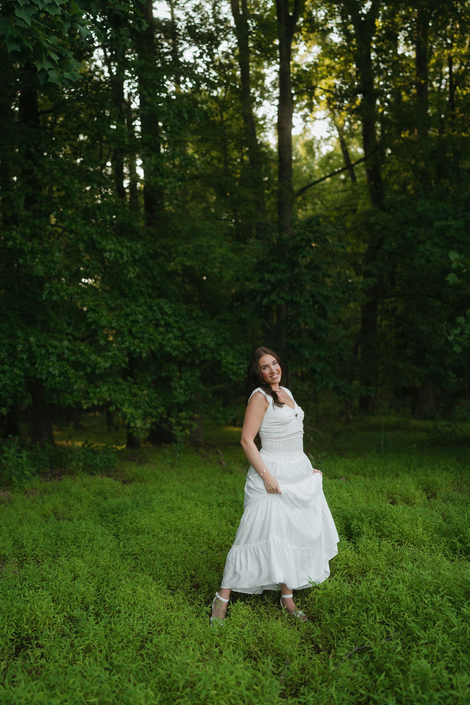 High school senior girl standing in a green field at Wilkerson Nature Preserve during a summer senior portrait session.