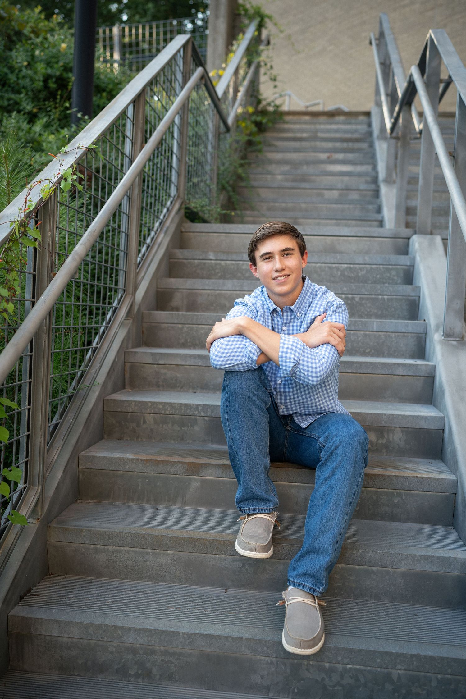 High school senior guy sitting on metal stairway at North Carolina Museum of Art in Raleigh, NC