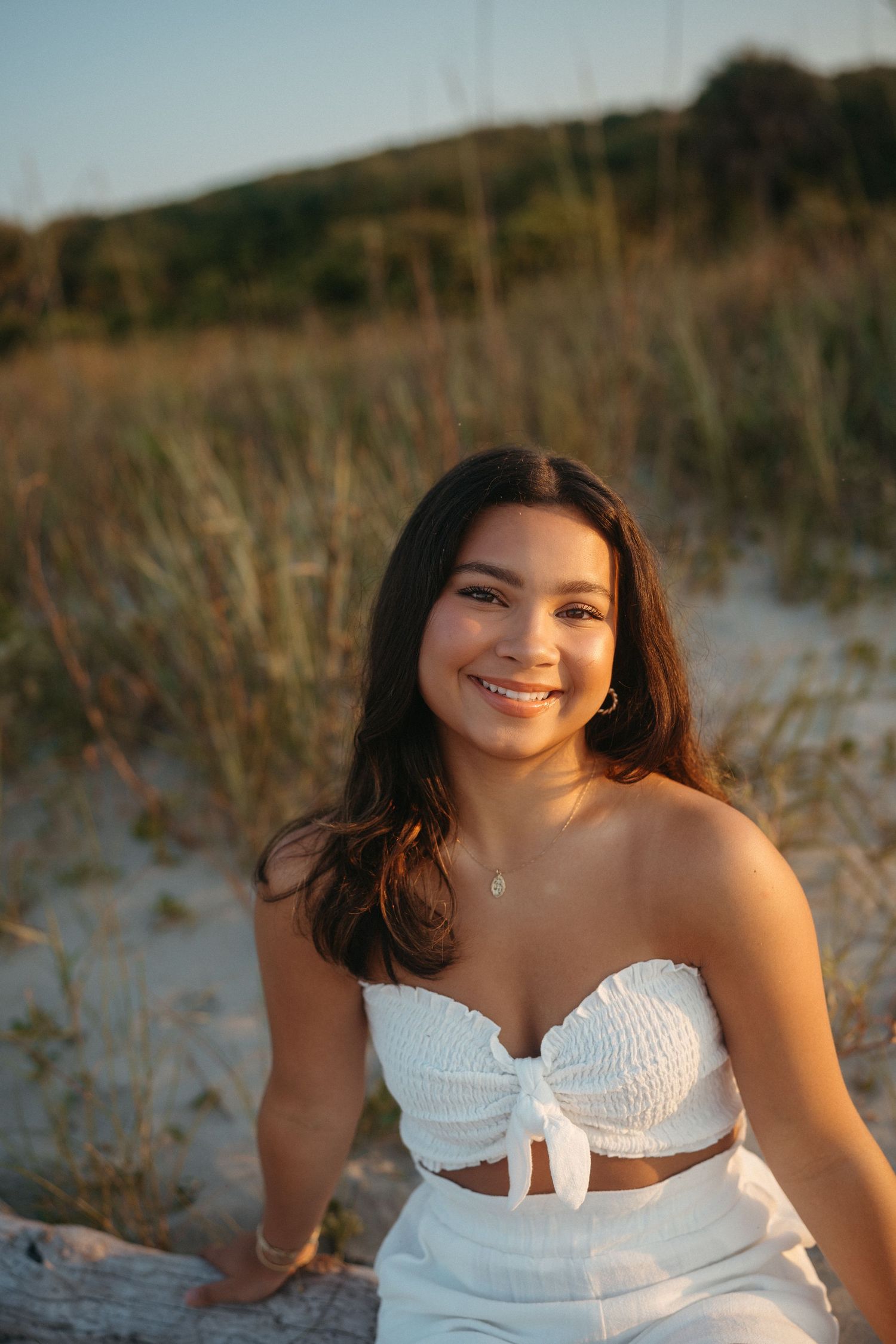 Close-up of a high school senior girl sitting in the sand at Folly Beach, South Carolina.
