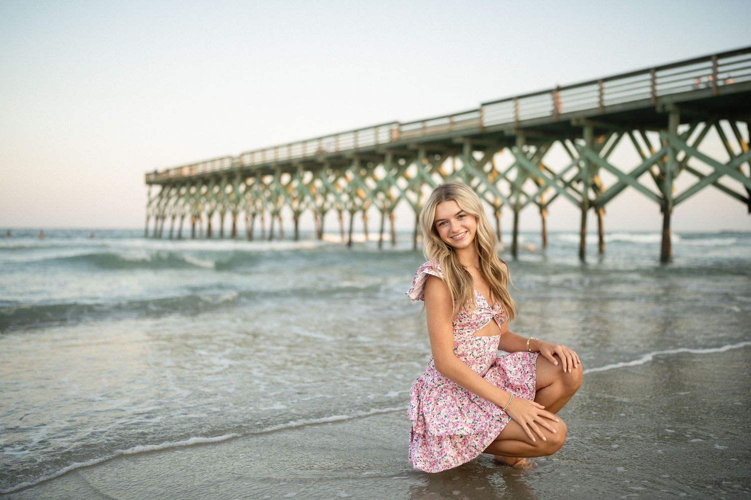 Senior portrait of Sydney at Wilmington, NC pier, showcasing a ocean backdrop during a beachside photo session