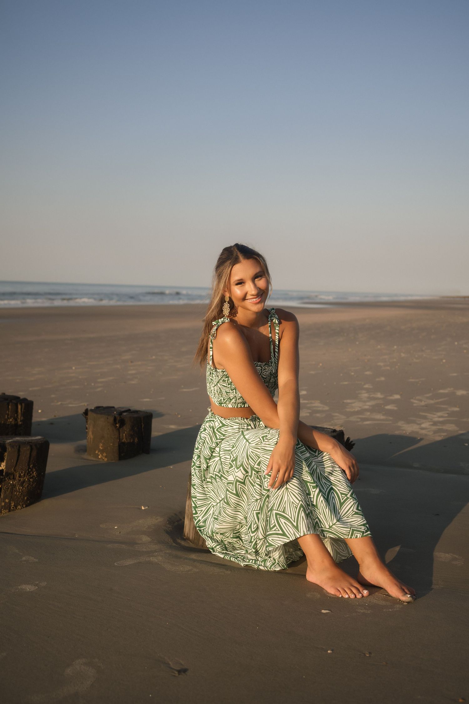 Sunrise senior photo at Folly Beach in a soft green floral two-piece maxi outfit.