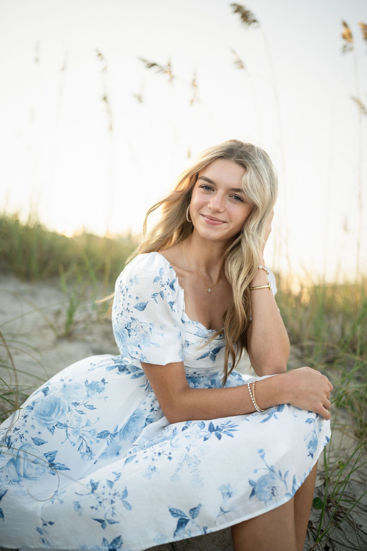 Sydney's senior photo session on Wilmington, NC beach, sitting in the sand during golden hour