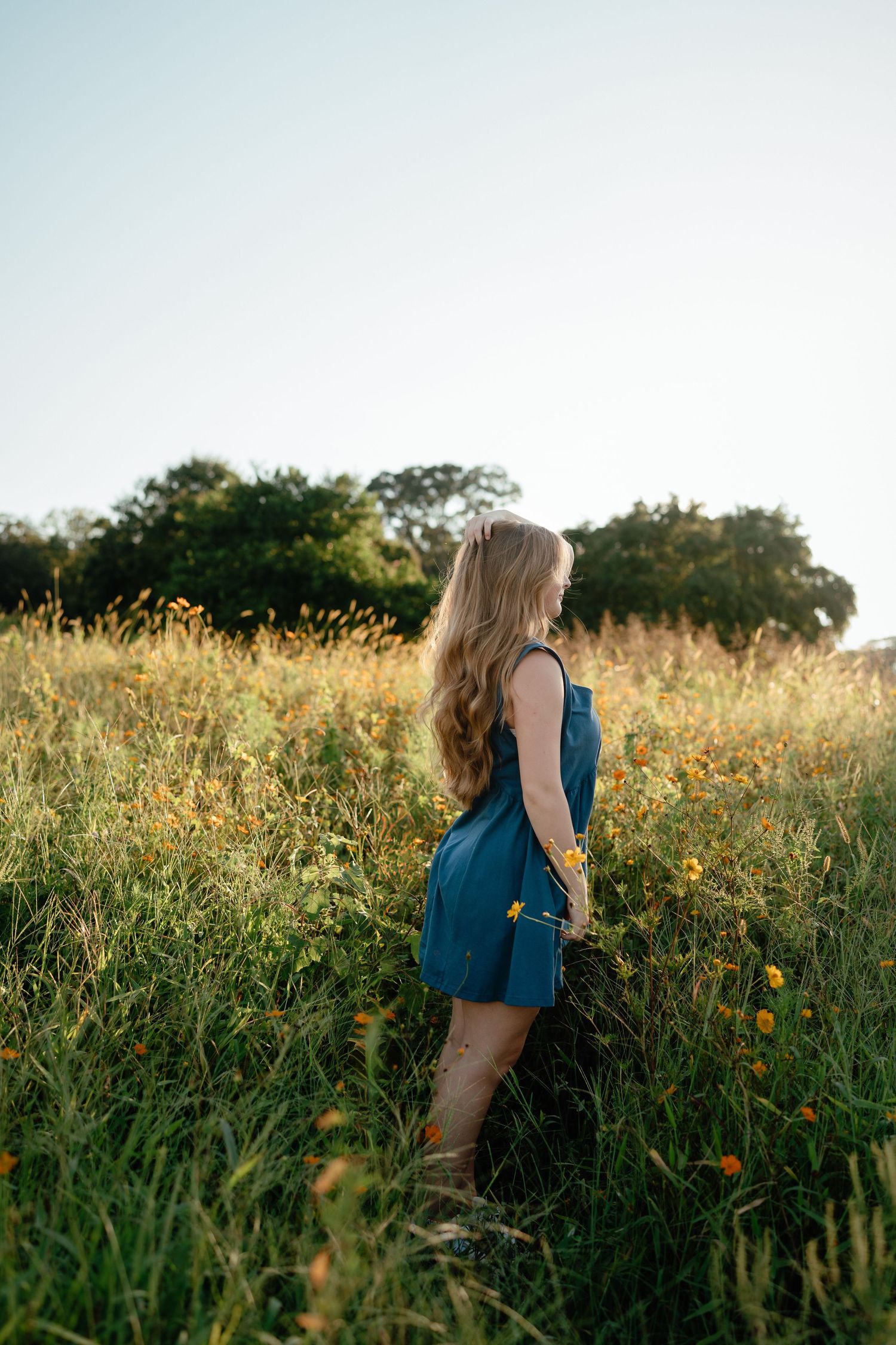 High school senior girl standing in tall grass at Dix Park in Raleigh, North Carolina.
