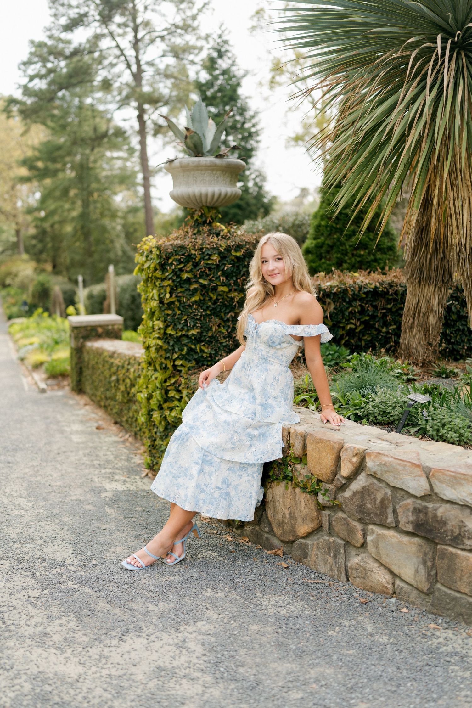 High school senior girl sitting on a wall at Duke Gardens in Durham, North Carolina during a spring senior session.