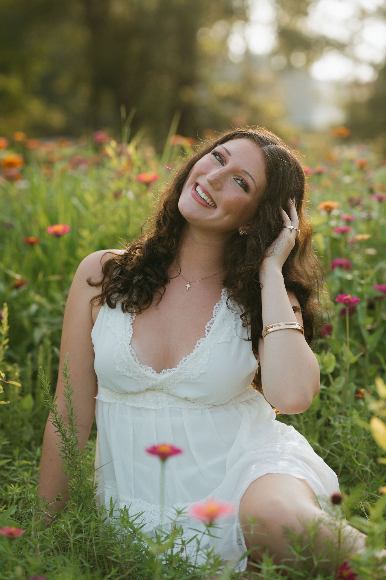 High school senior girl in a white dress sitting in the wildflowers in Raleigh, North Carolina.