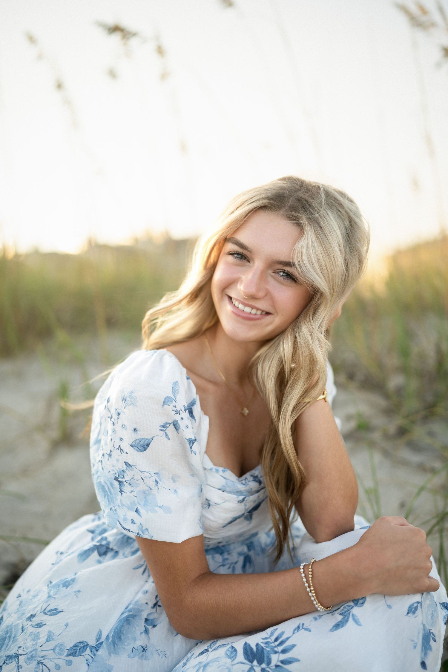 Sydney's senior photo session on Wilmington, NC beach, sitting in the sand during golden hour