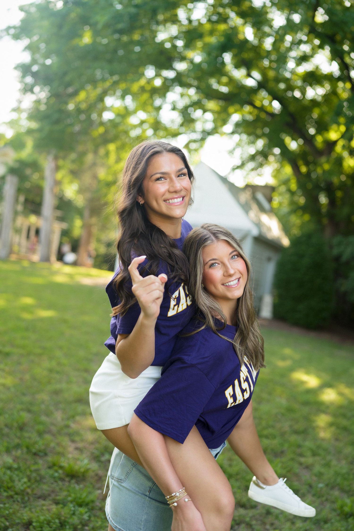Two high school seniors wearing ECU shirts and posing together during a senior photo session at Historic Oak View County Park in Raleigh.