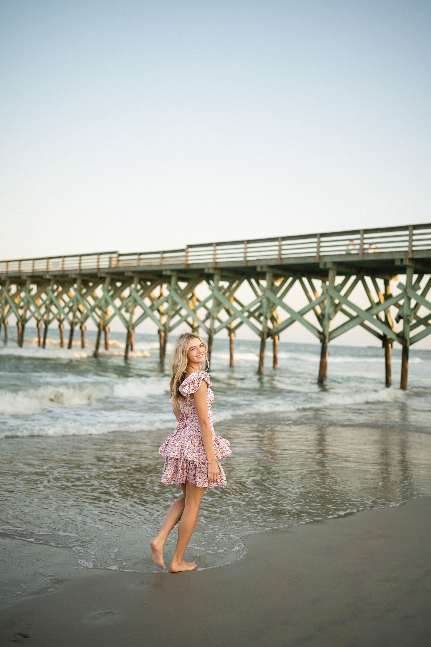 Senior portrait of Sydney at Wilmington, NC pier, showcasing a ocean backdrop during a beachside photo session