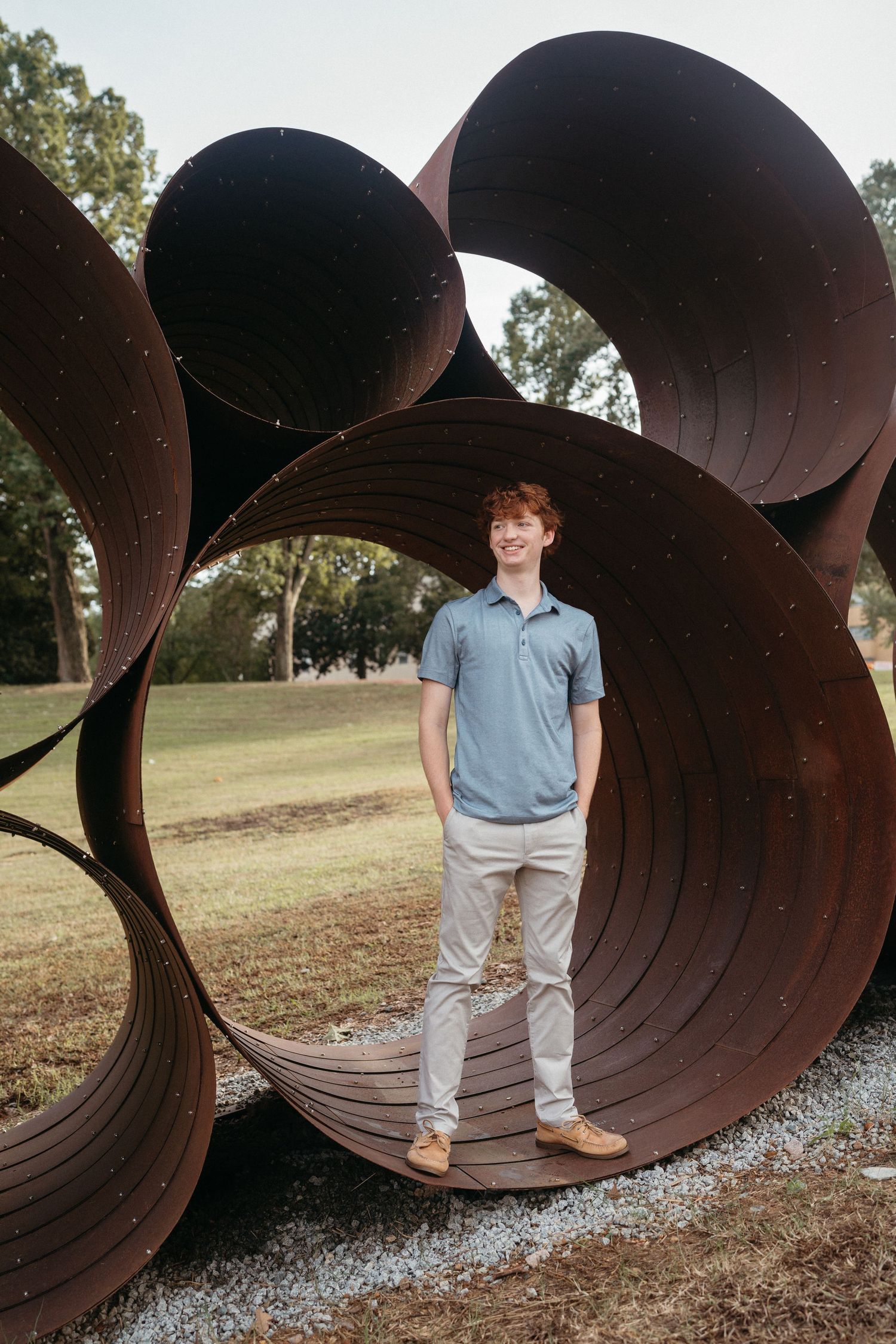 High school senior guy standing inside pipe sculpture at Dorothea Dix Park in Raleigh, NC