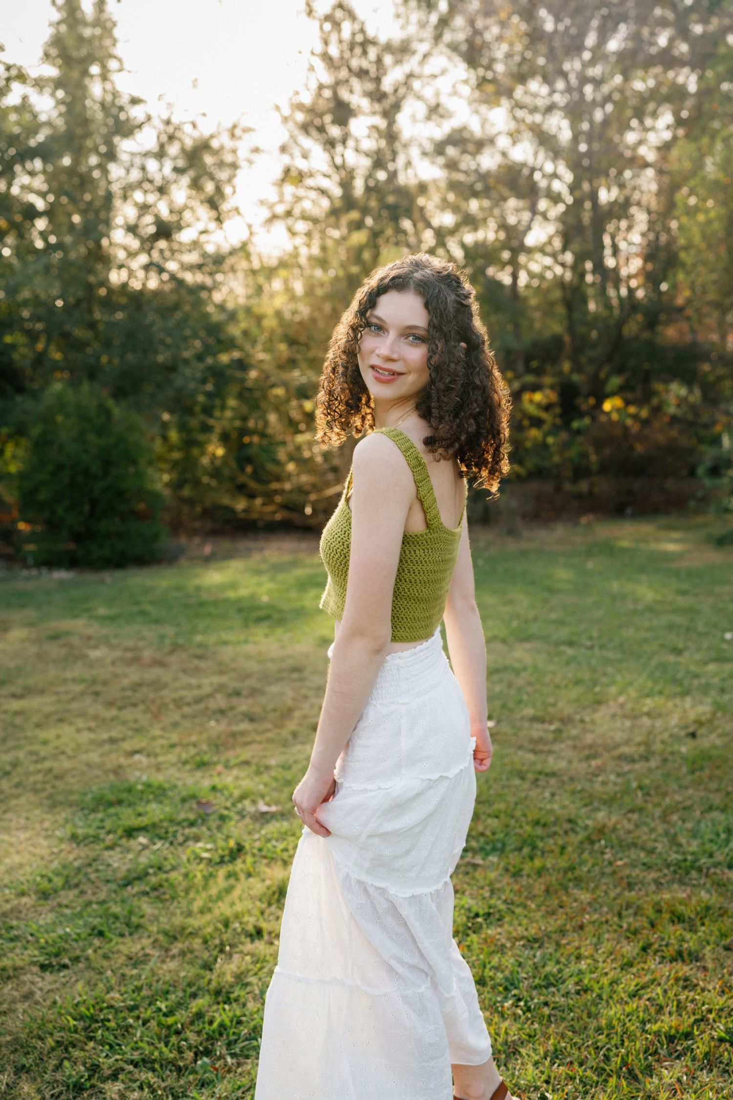 High school senior girl walking and playing with her skirt at JC Raulston Arboretum in Raleigh.