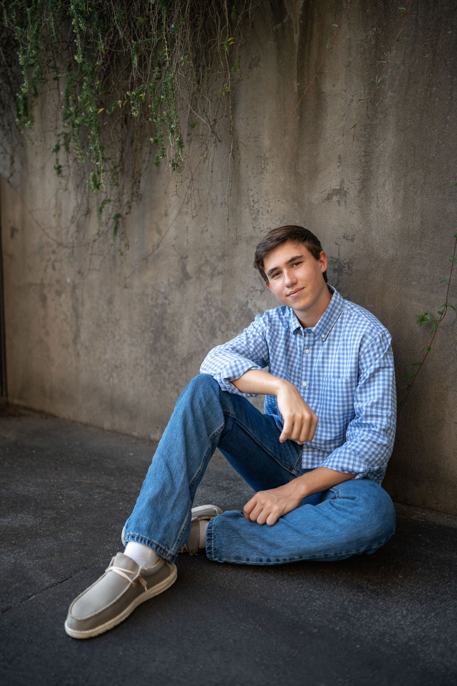 Senior boy leaning against concrete wall at North Carolina Museum of Art in Raleigh