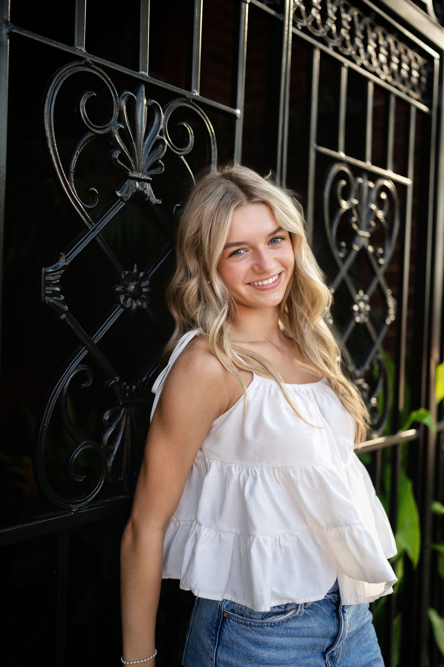 Sydney's senior portrait at a gated home entrance in downtown Wilmington, NC, featuring elegant ironwork and greenery