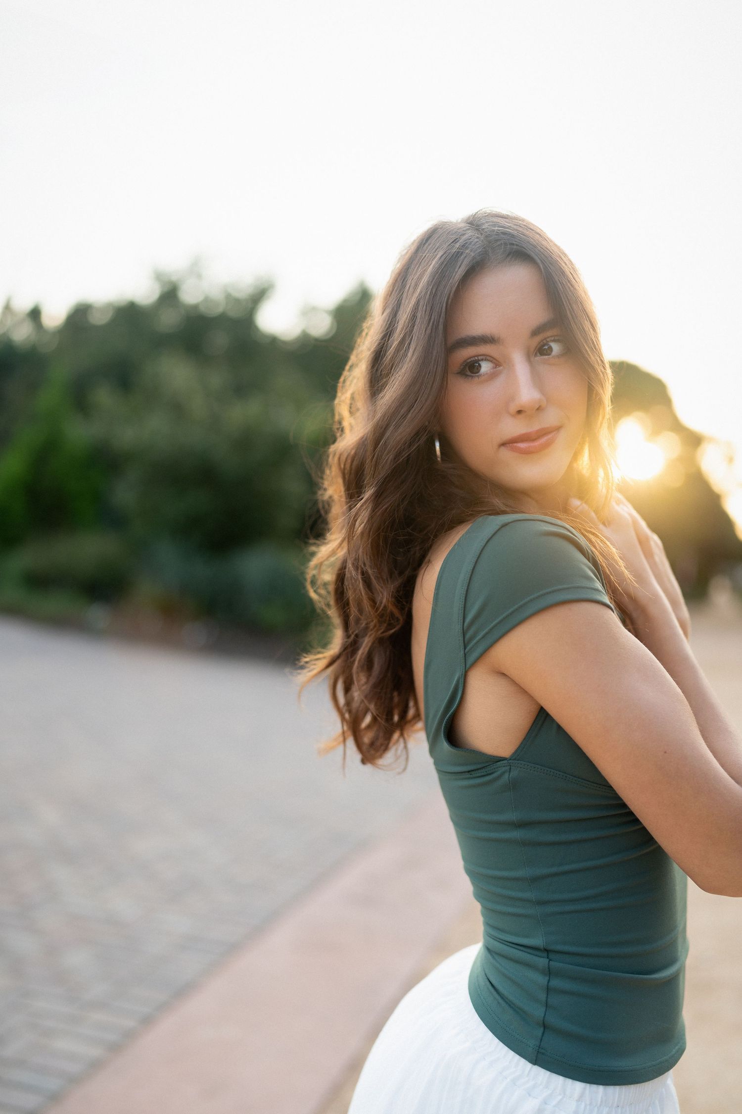 Close-up of a high school senior girl with sunlight behind her at JC Raulston Arboretum in Raleigh.