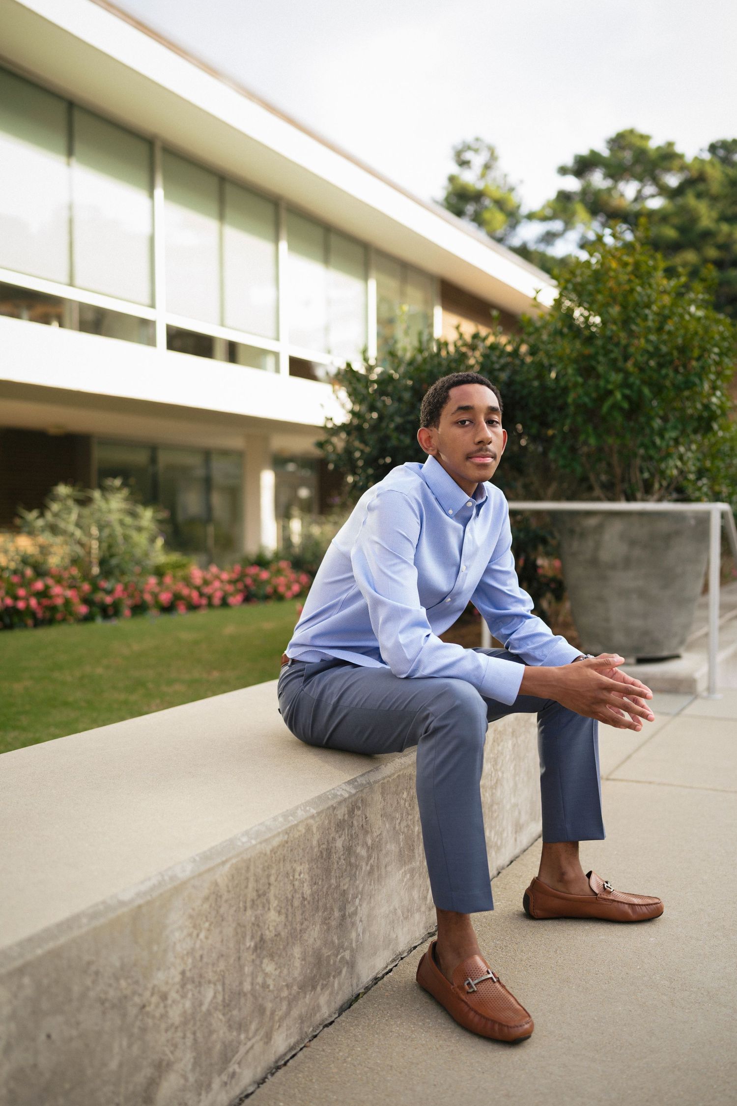 Senior boy sitting on concrete with flowers at WRAL Azalea Garden in Raleigh