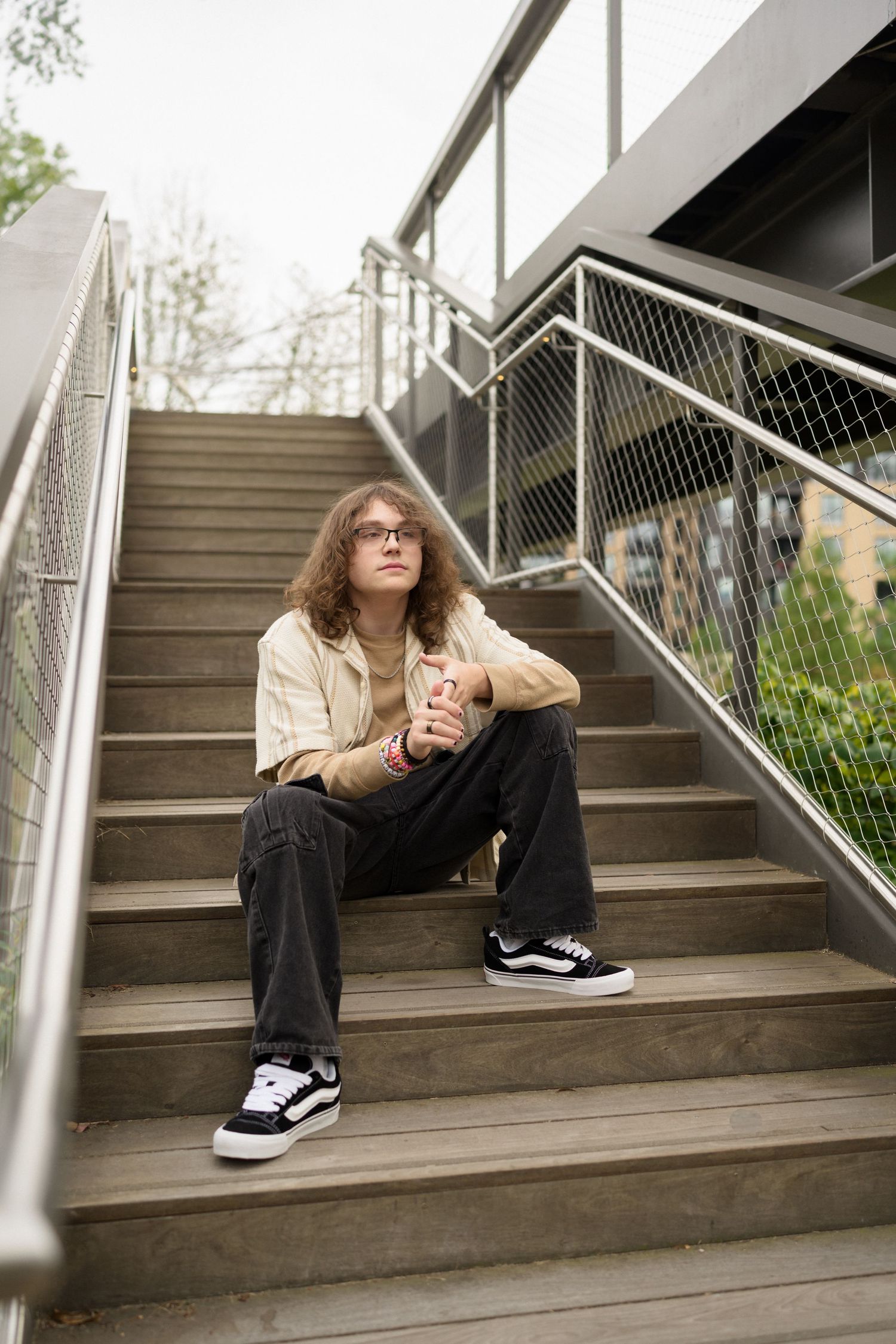 High school senior guy sitting on stairs at Downtown Cary Park in Cary, NC