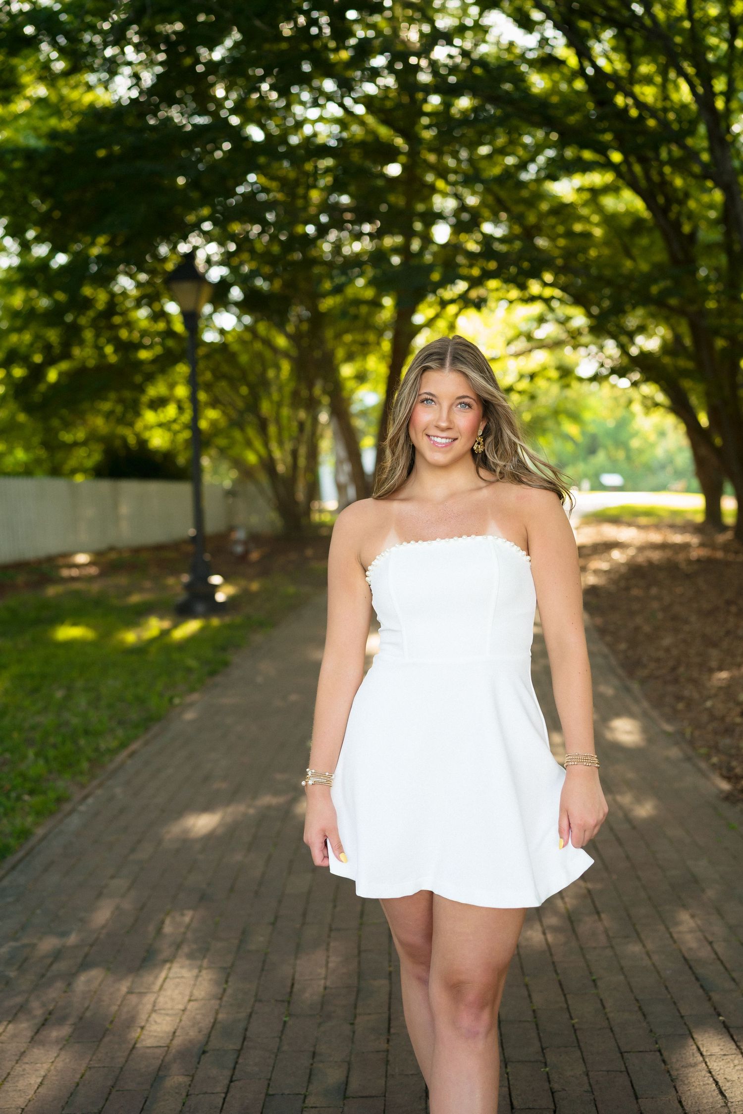 High school senior girl in a white dress during her senior portraits at Historic Oak View County Park in Raleigh.
