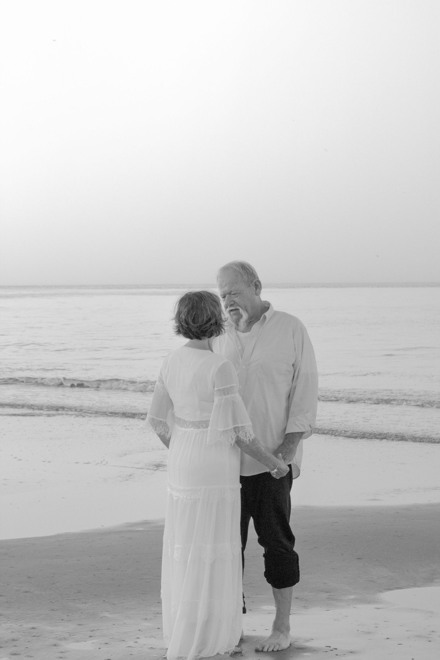 A romantic black and white beach photo series with soft waves and cloudy skies.