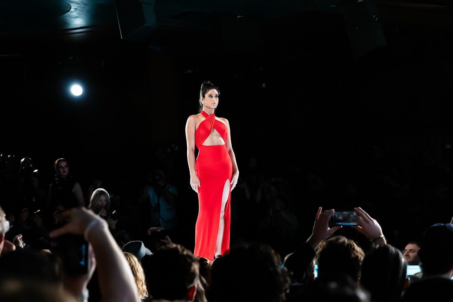 Models walk the runway in red evening gowns during a fashion show presentation.