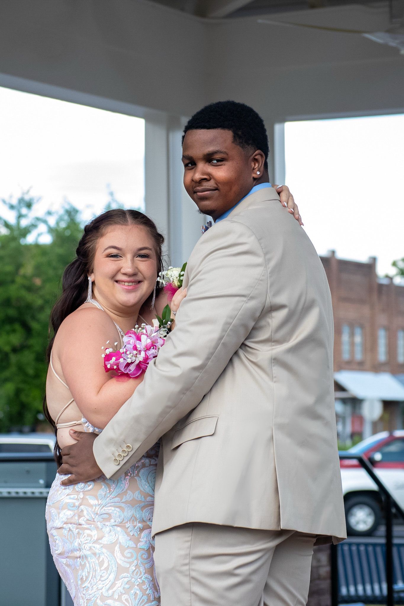 A couple shares an intimate dance moment in formal attire at an outdoor venue.