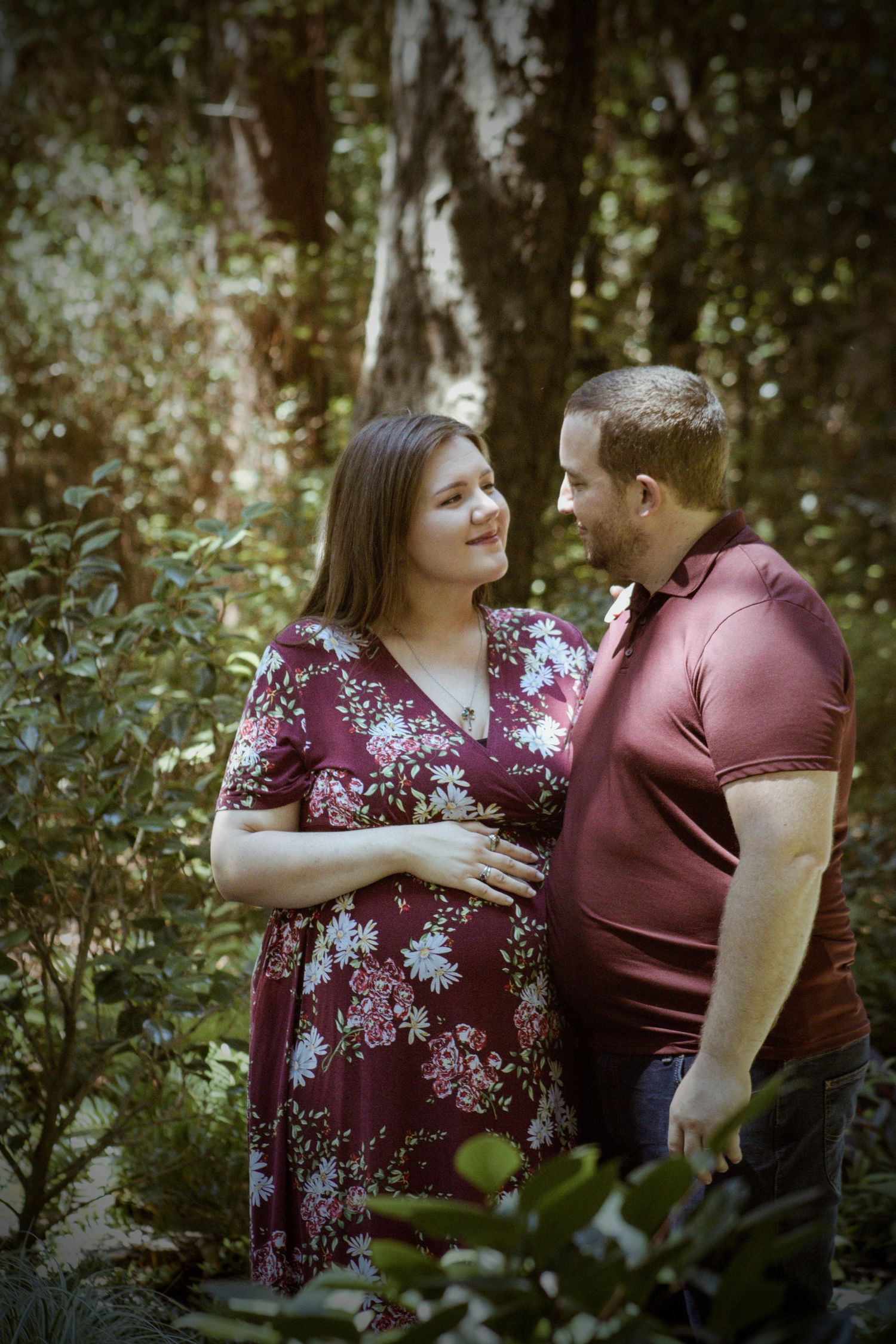 A romantic garden photoshoot featuring matching burgundy outfits and natural foliage in the background.