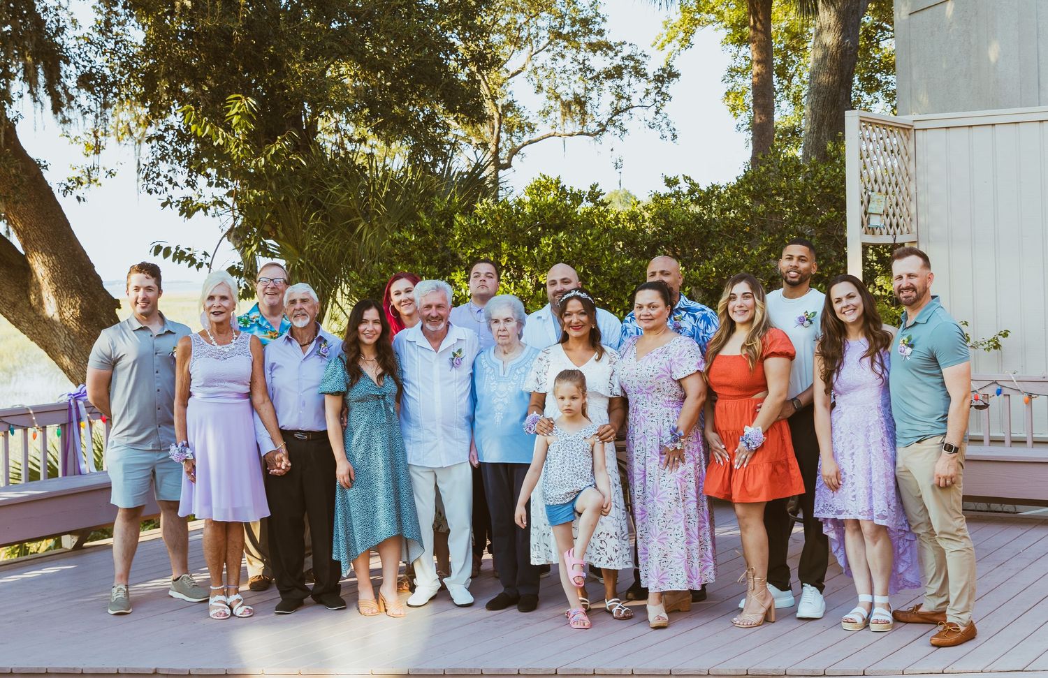 A large family group poses together outdoors wearing coordinated pastel blue and pink outfits on a sunny day.