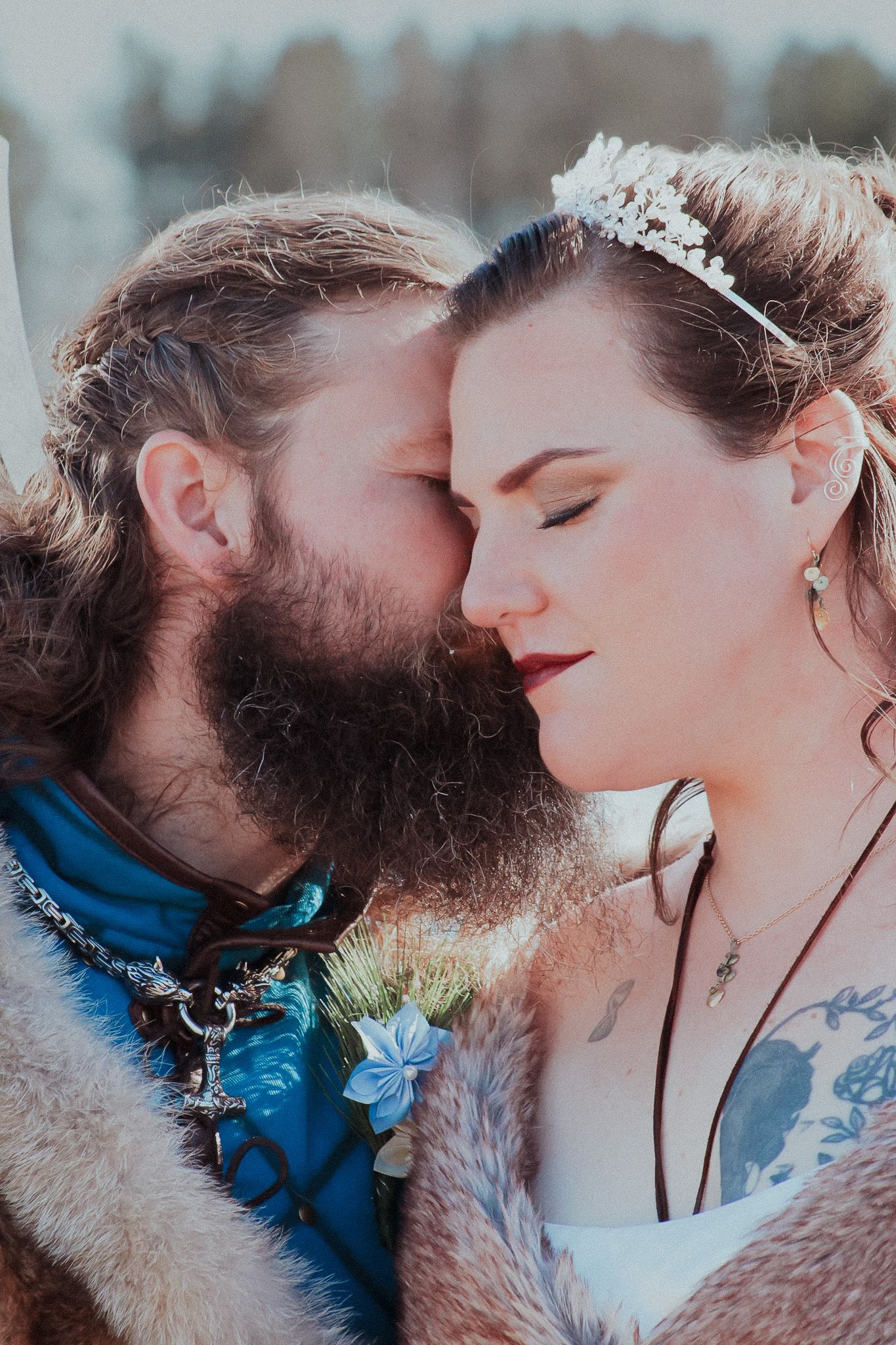 Intimate romantic moment between couple in wedding attire with groom in fur and blue accessories.