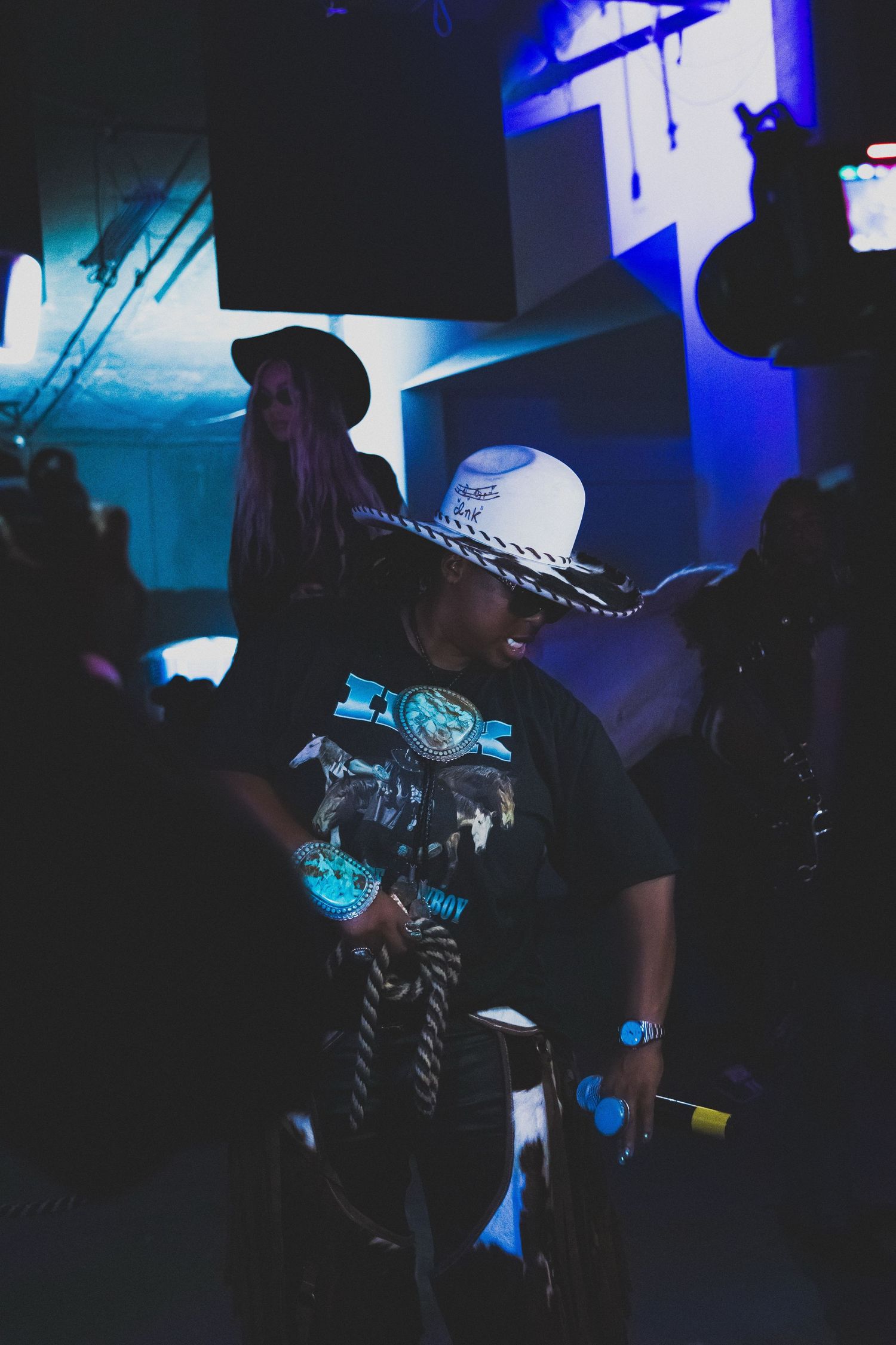 Concert performers silhouetted against blue stage lighting during live show.