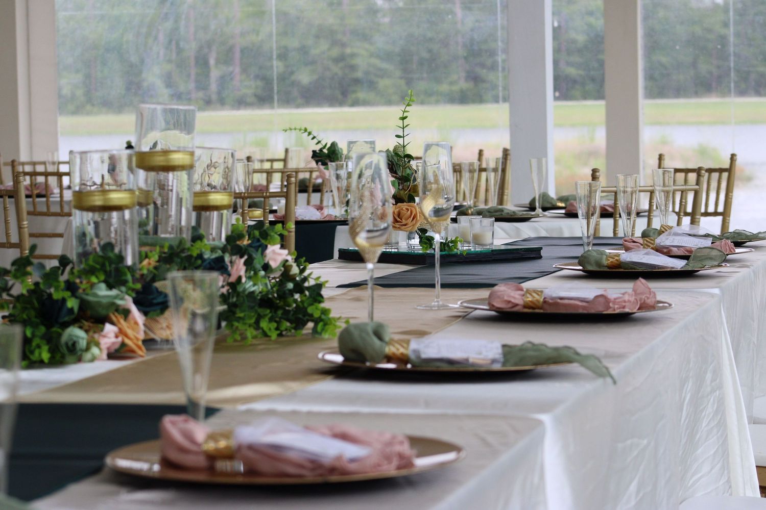 Wedding reception table with elegant place settings, gold chairs and floral decorations.