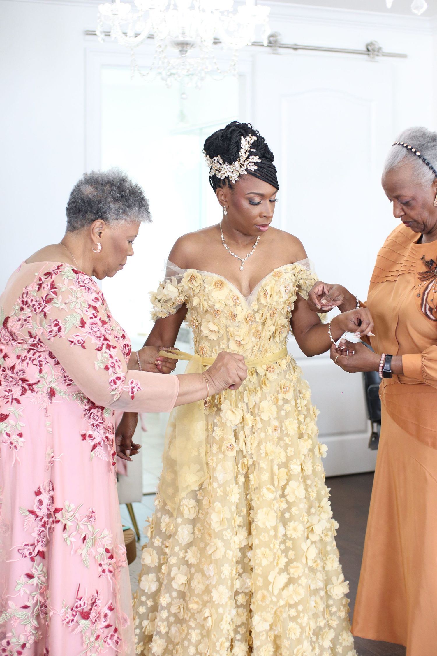 Wedding dress fitting scene with elegant yellow ball gown and helpers making adjustments.