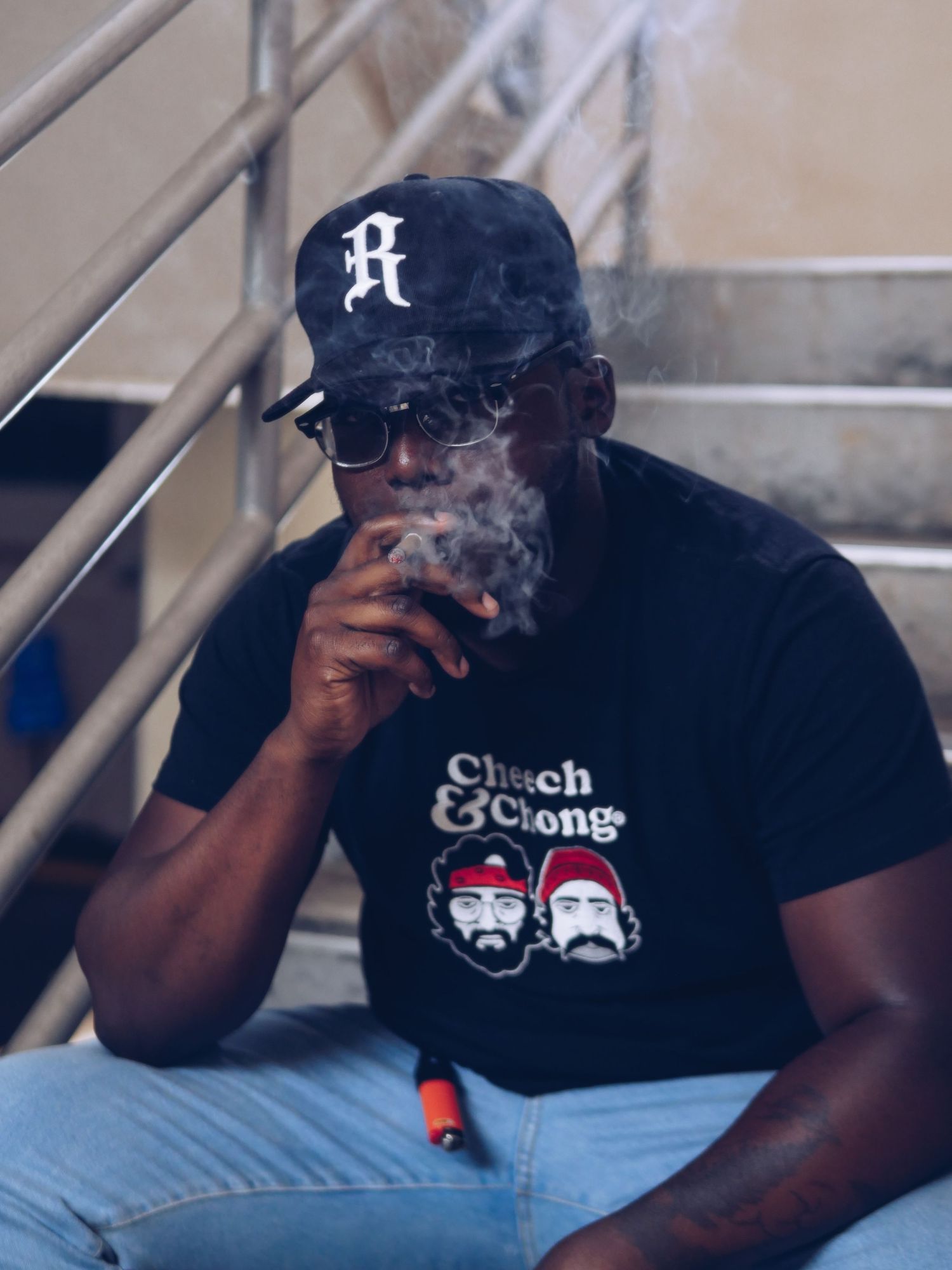 Person wearing baseball cap and graphic t-shirt relaxing outdoors.