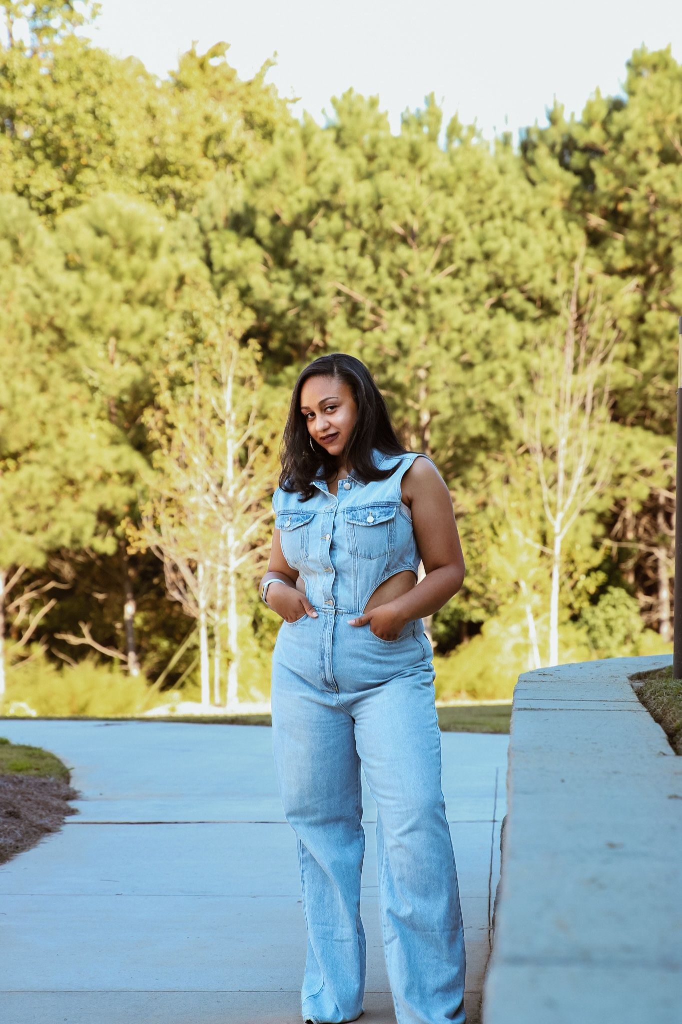 Casual outdoor photoshoot in light denim against a pine forest backdrop.