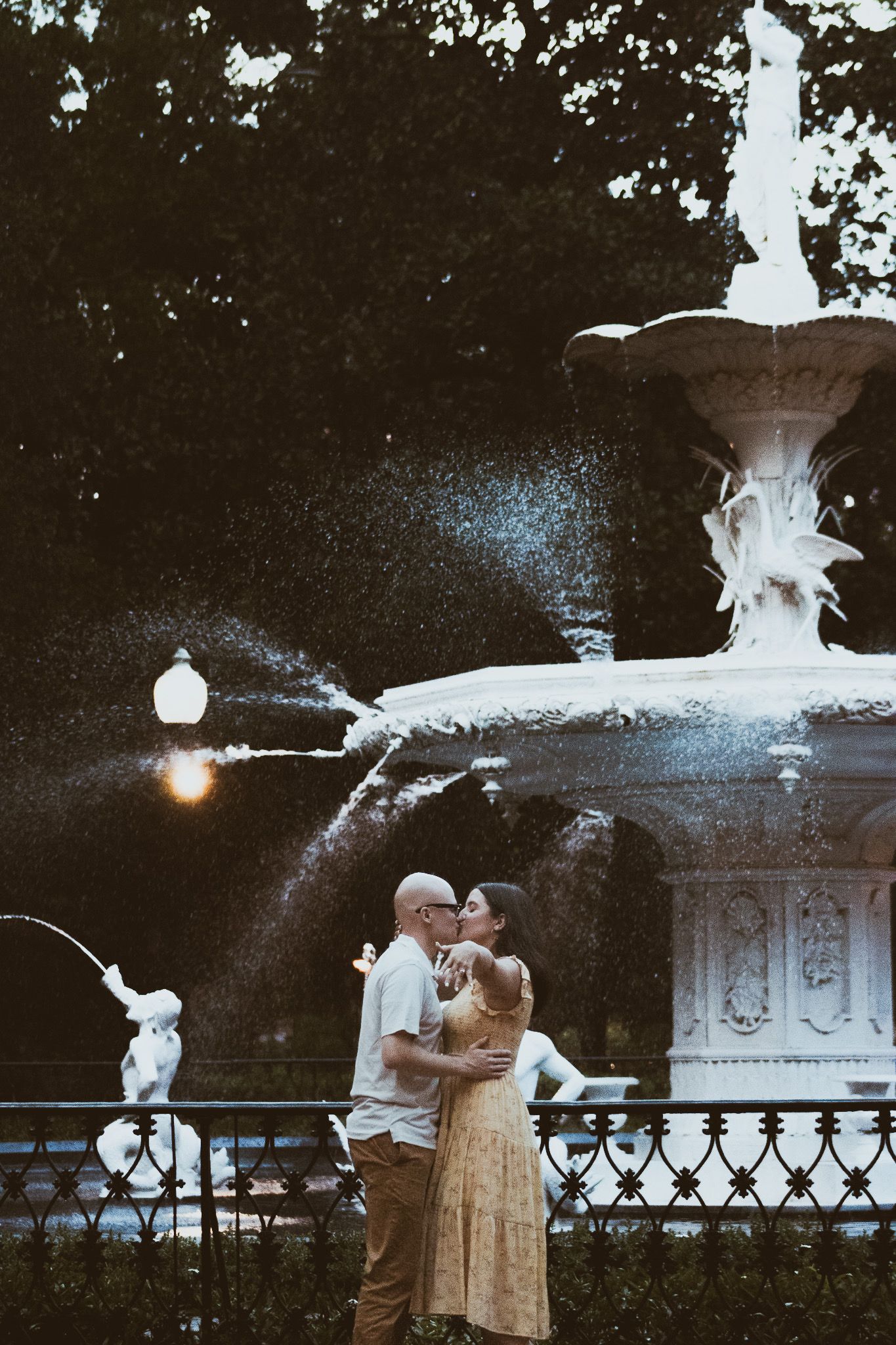 Romantic nighttime scene by an ornate fountain with illuminated water features.